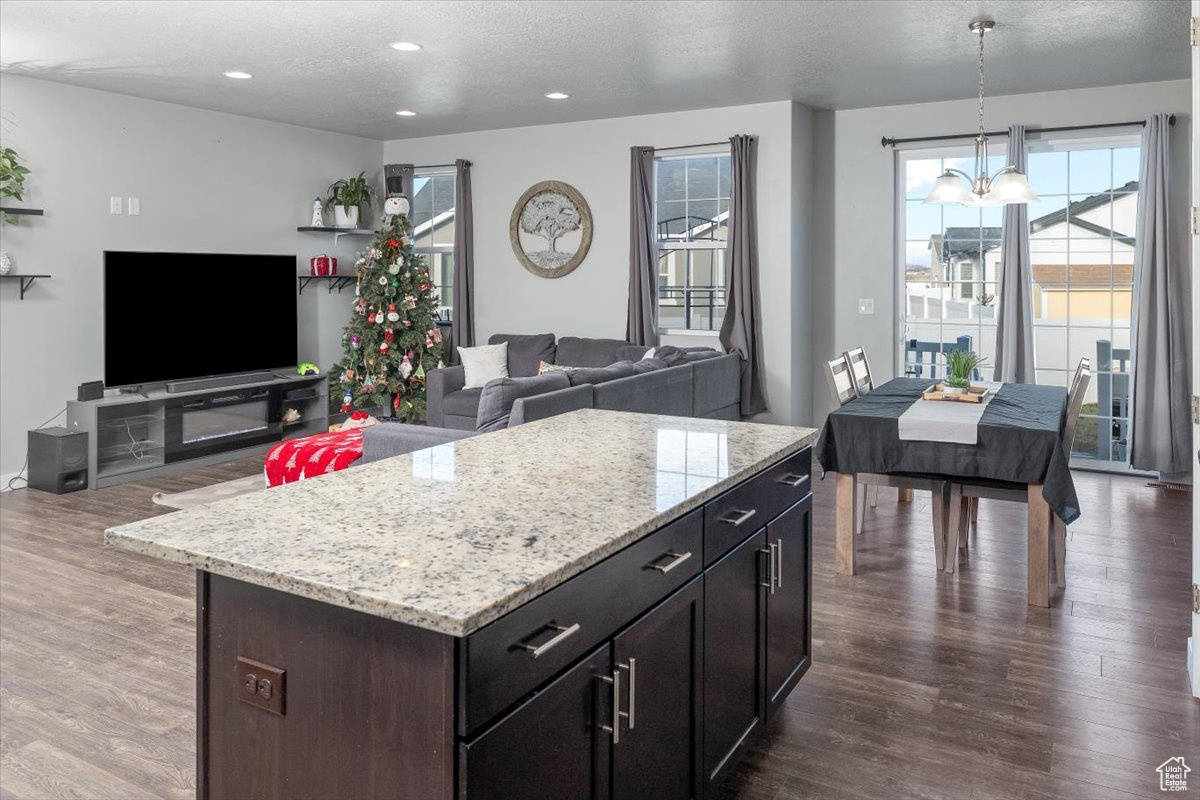 Kitchen featuring pendant lighting, dark hardwood / wood-style flooring, a center island, and a notable chandelier