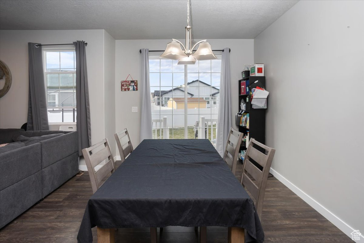 Dining space with a textured ceiling, dark hardwood / wood-style flooring, and an inviting chandelier