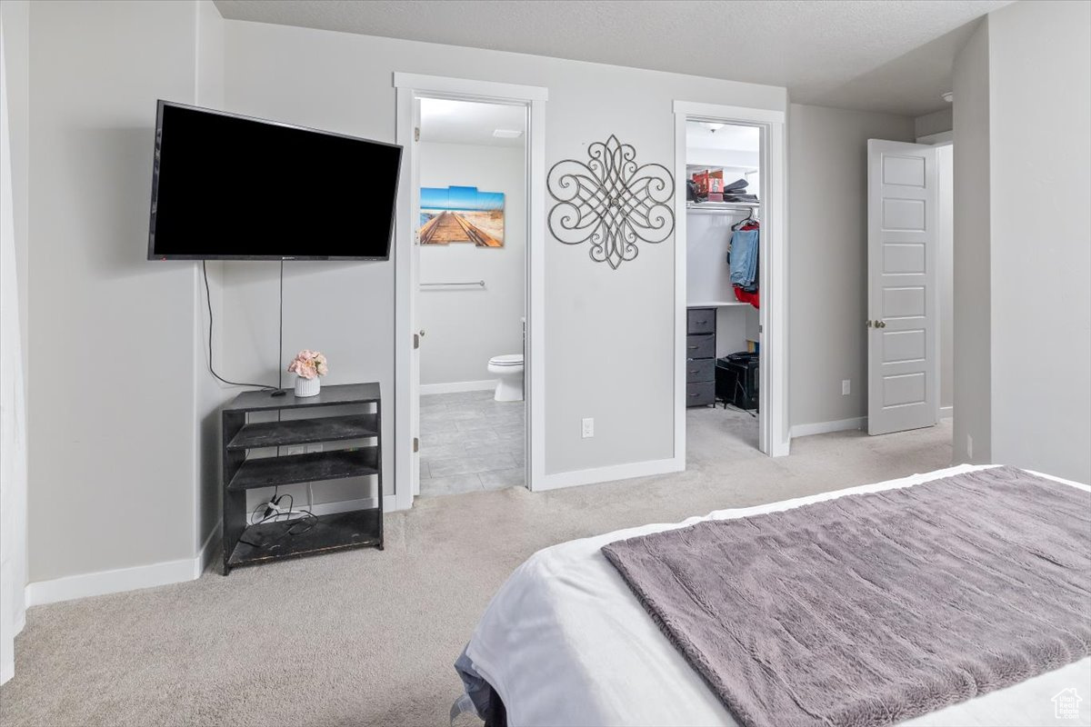 Carpeted bedroom with connected bathroom, a walk in closet, and a closet