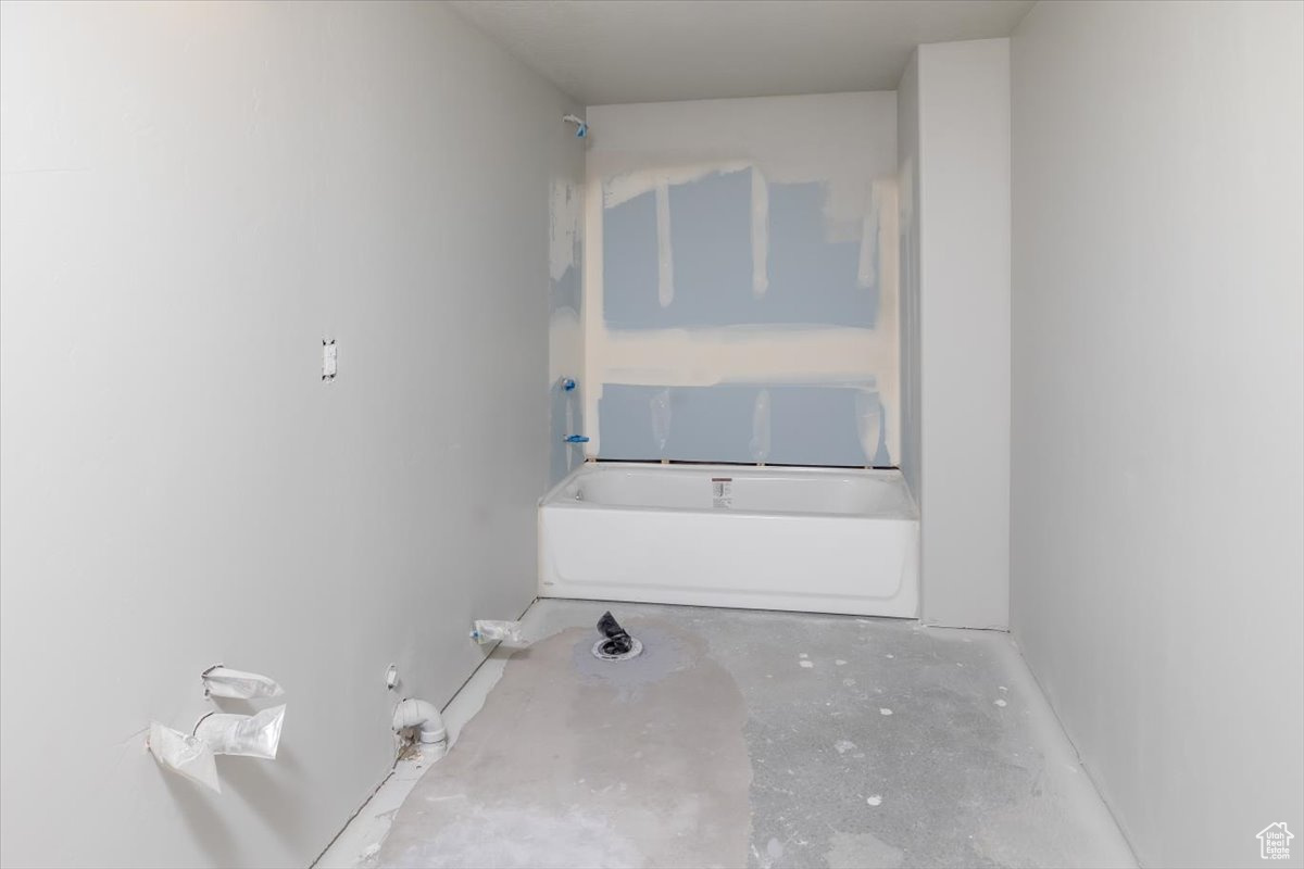 Bathroom featuring concrete flooring and a tub