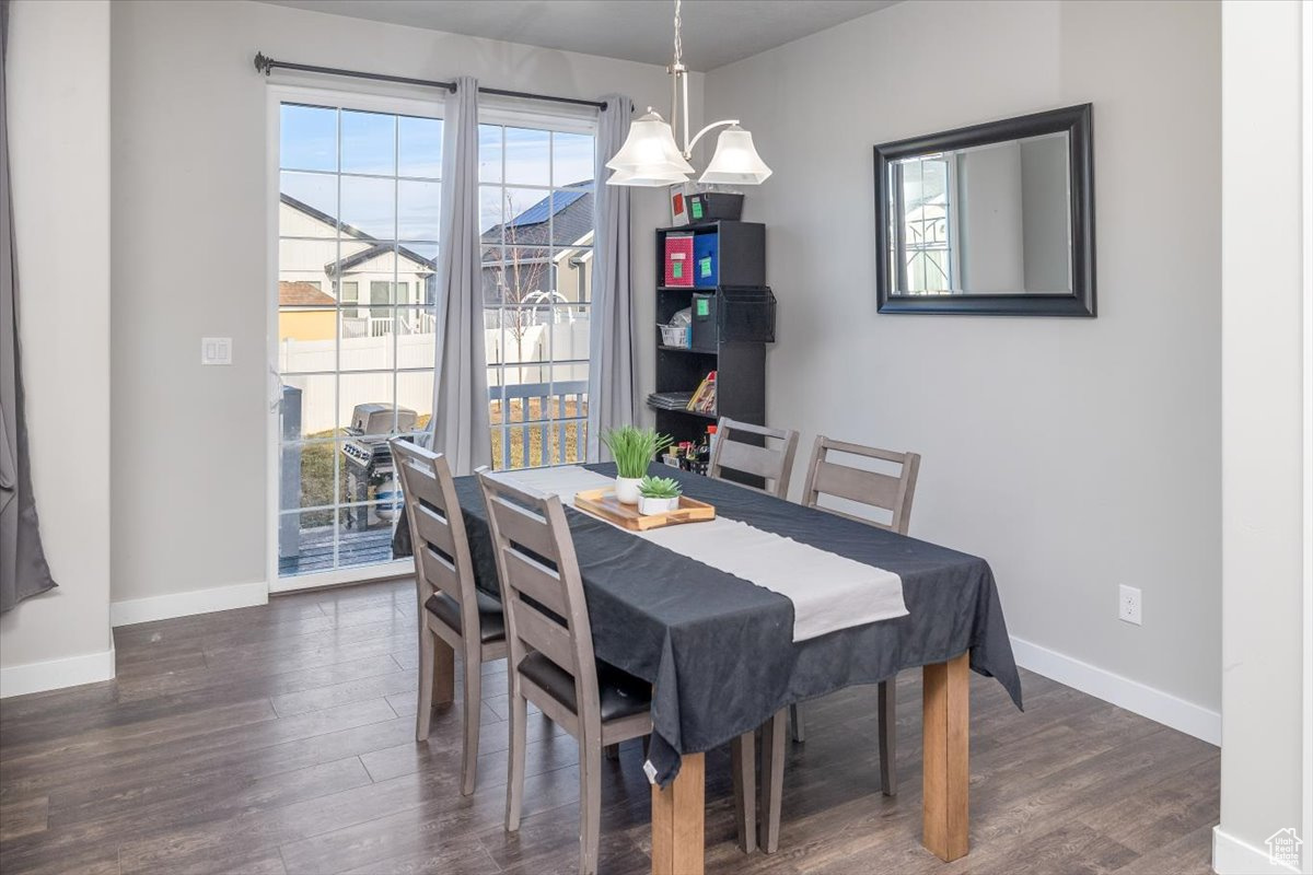 Dining space with dark hardwood / wood-style floors and an inviting chandelier