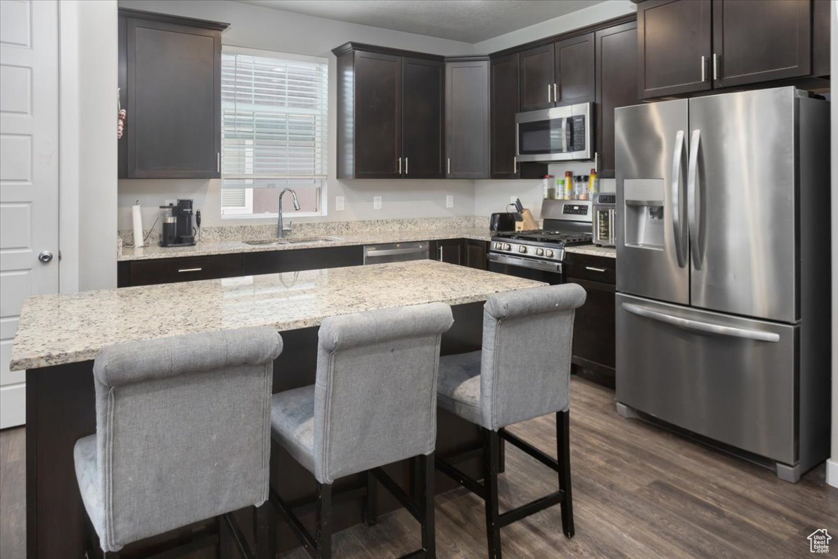 Kitchen with a breakfast bar, a center island, dark wood-type flooring, sink, and stainless steel appliances