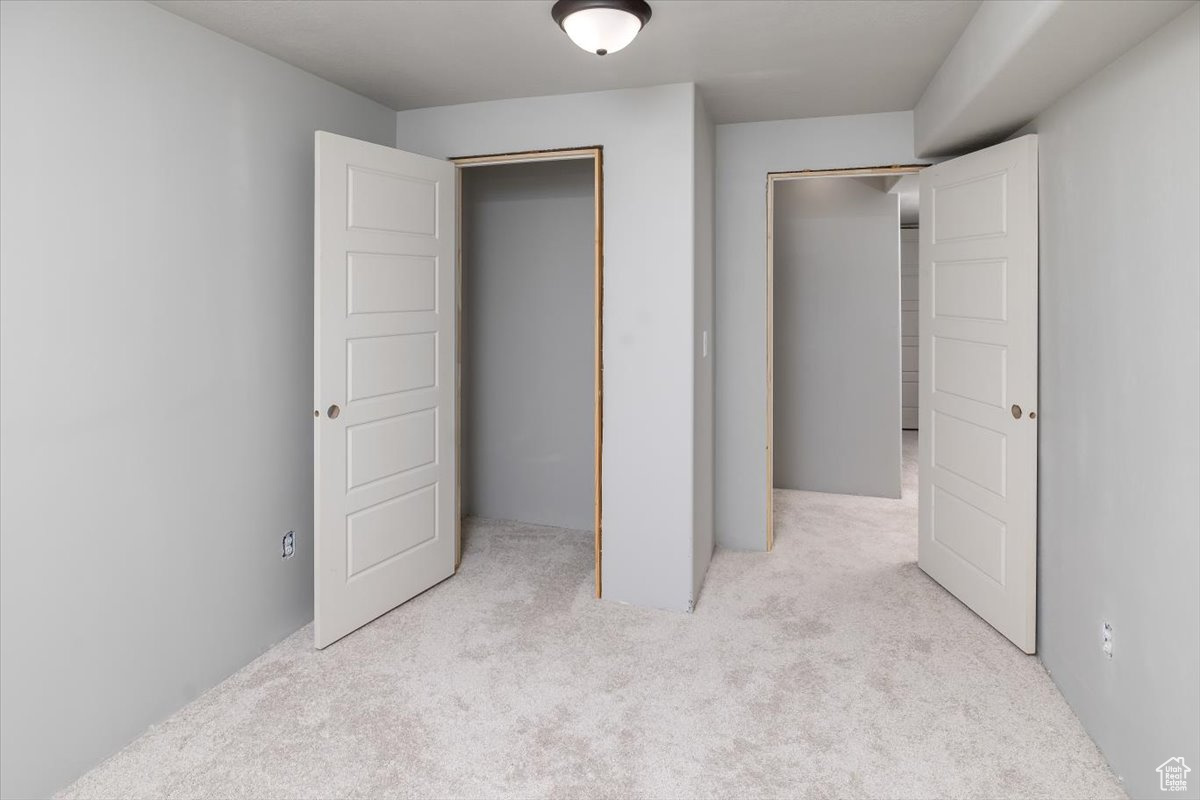 Unfurnished bedroom with light colored carpet and a closet