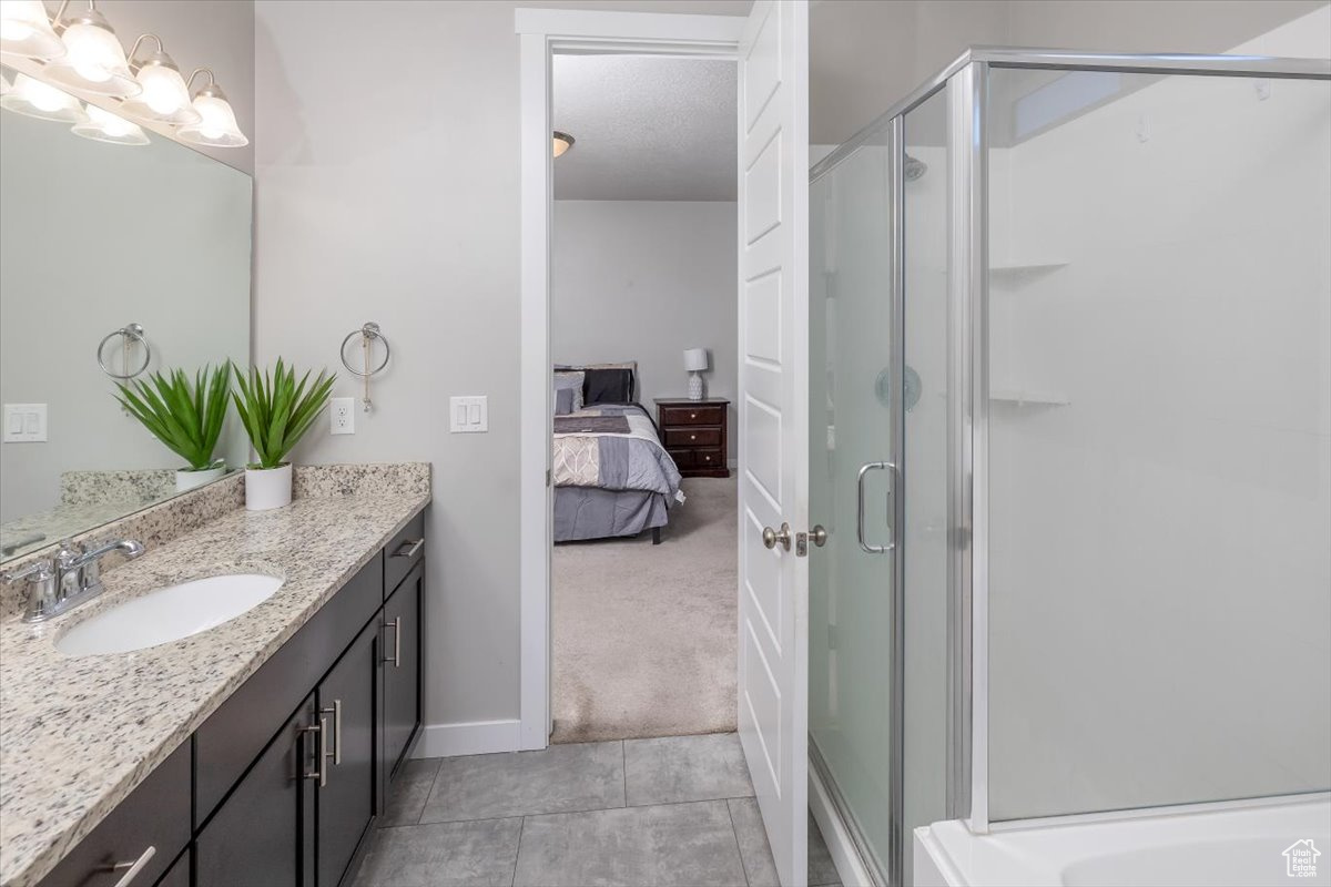 Bathroom with tile patterned floors, vanity, and an enclosed shower