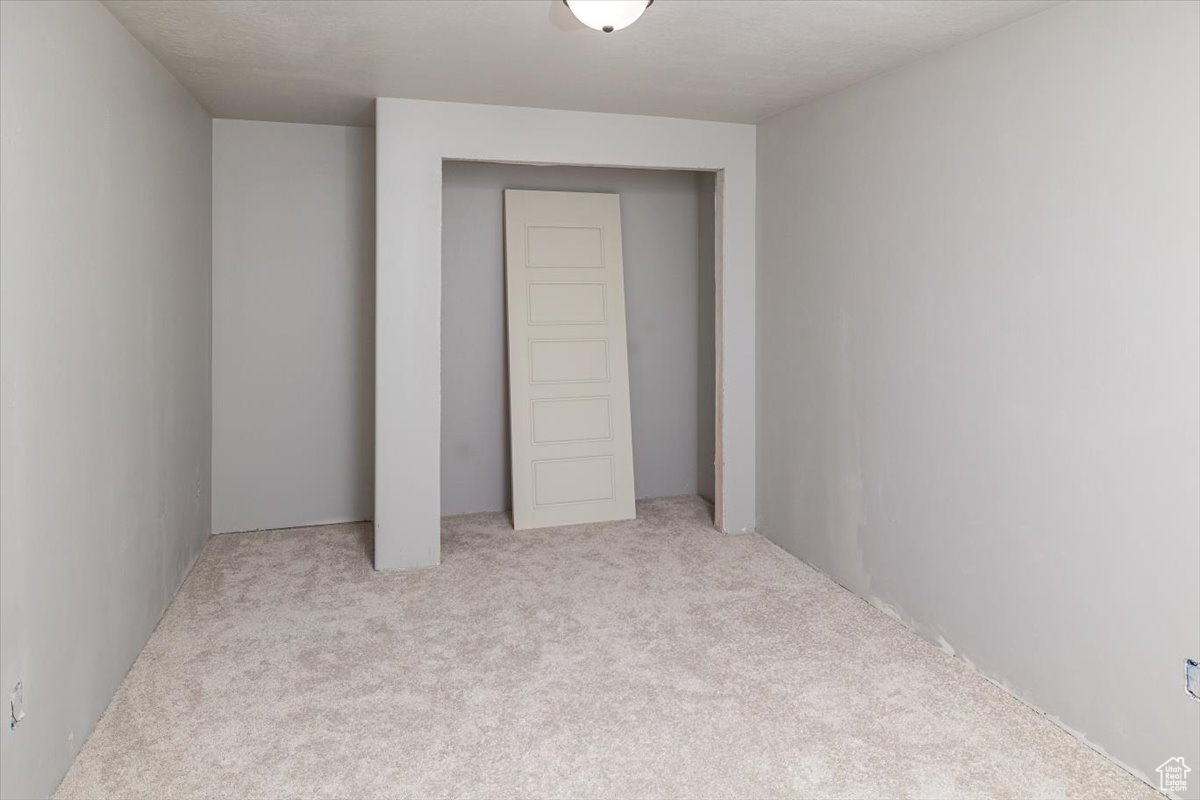 Unfurnished bedroom with light colored carpet and a closet