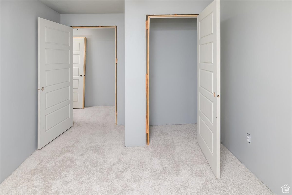 Unfurnished bedroom featuring a closet and light colored carpet