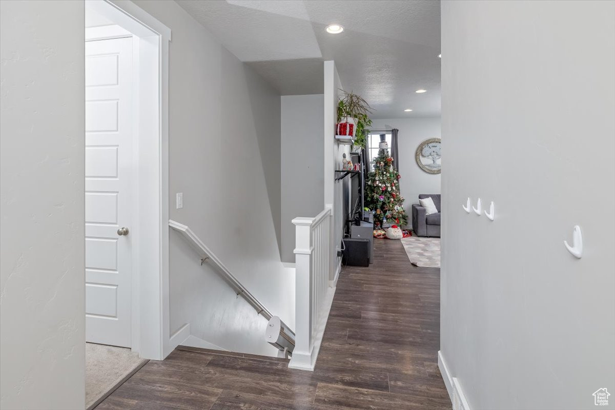 Hallway featuring a textured ceiling and dark hardwood / wood-style floors