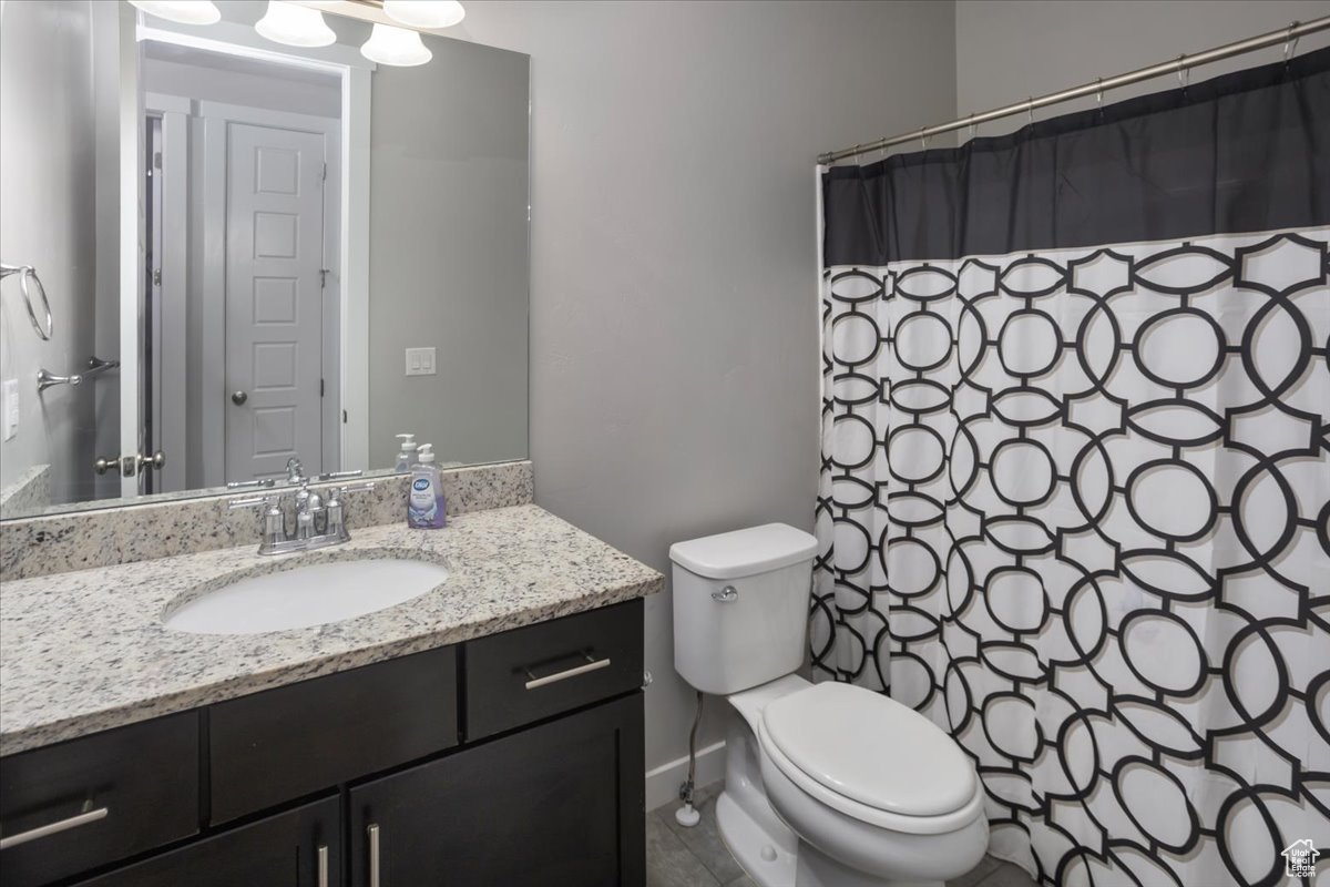 Bathroom with tile patterned floors, vanity, curtained shower, and toilet