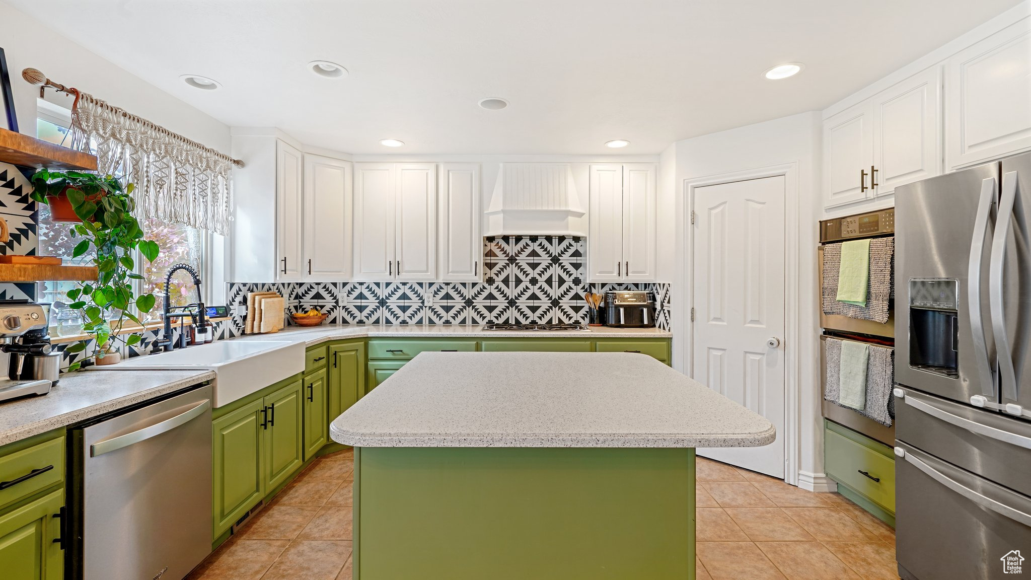 Kitchen featuring appliances with stainless steel finishes, backsplash, sink, a center island, and white cabinetry