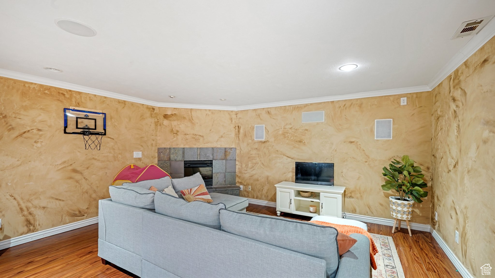 Living room with wood-type flooring, ornamental molding, and a tiled fireplace