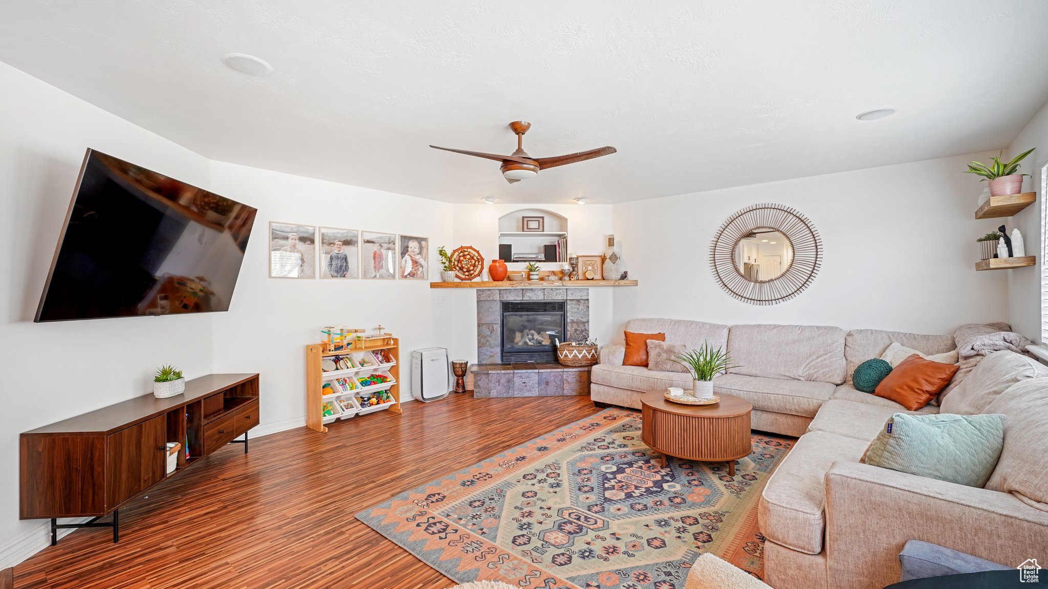 Living room featuring a tile fireplace, hardwood / wood-style floors, and ceiling fan