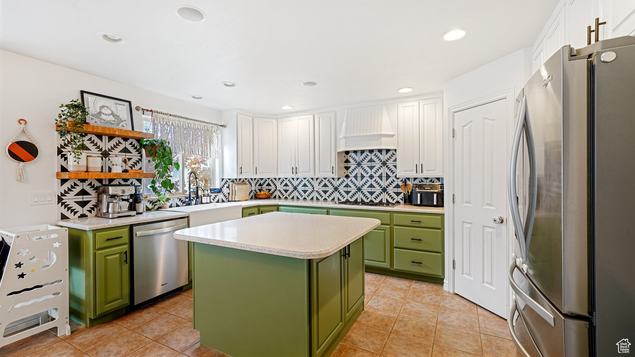 Kitchen featuring white cabinets, a center island, green cabinets, and appliances with stainless steel finishes