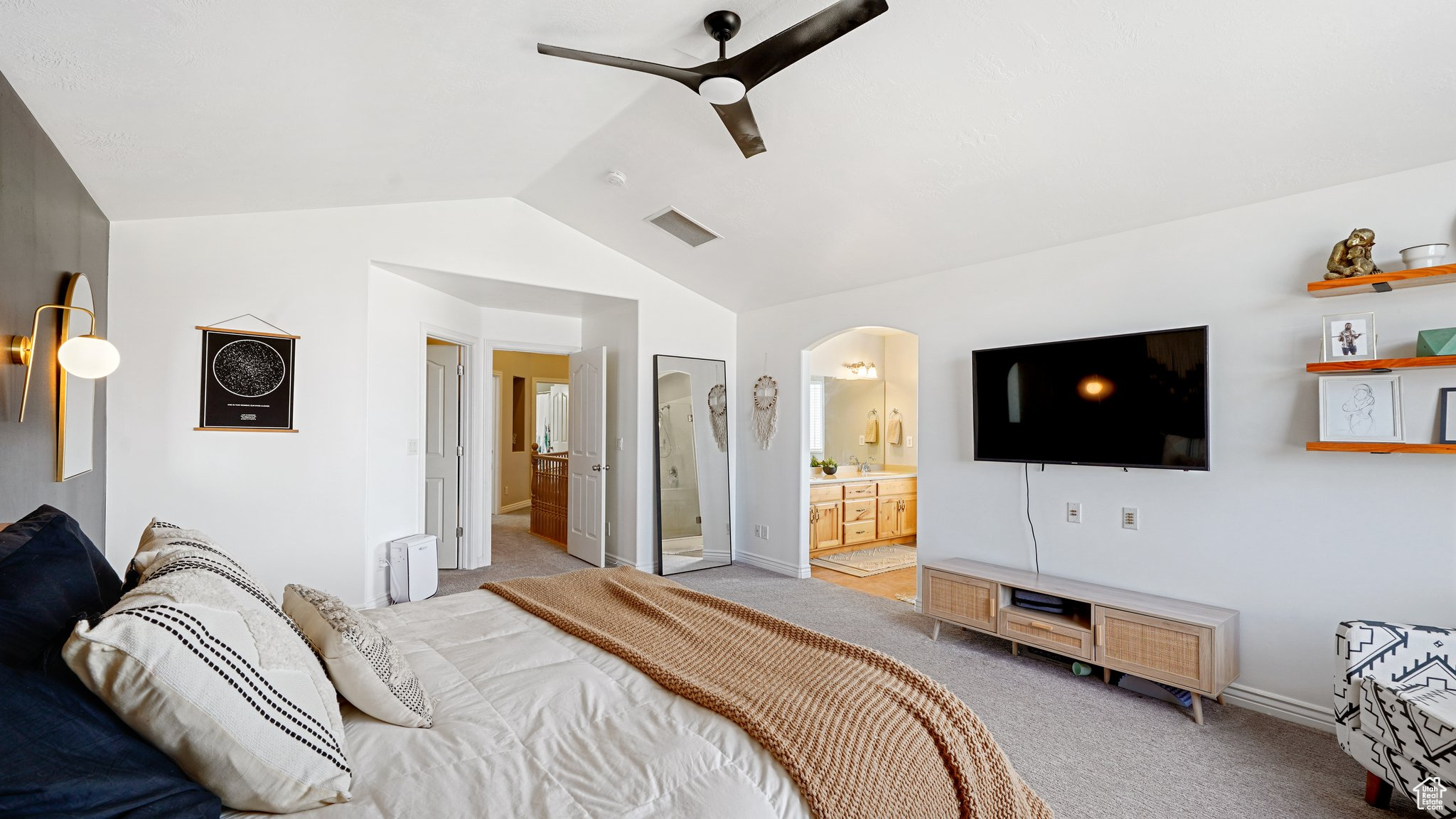 Carpeted bedroom featuring ensuite bathroom, ceiling fan, and vaulted ceiling