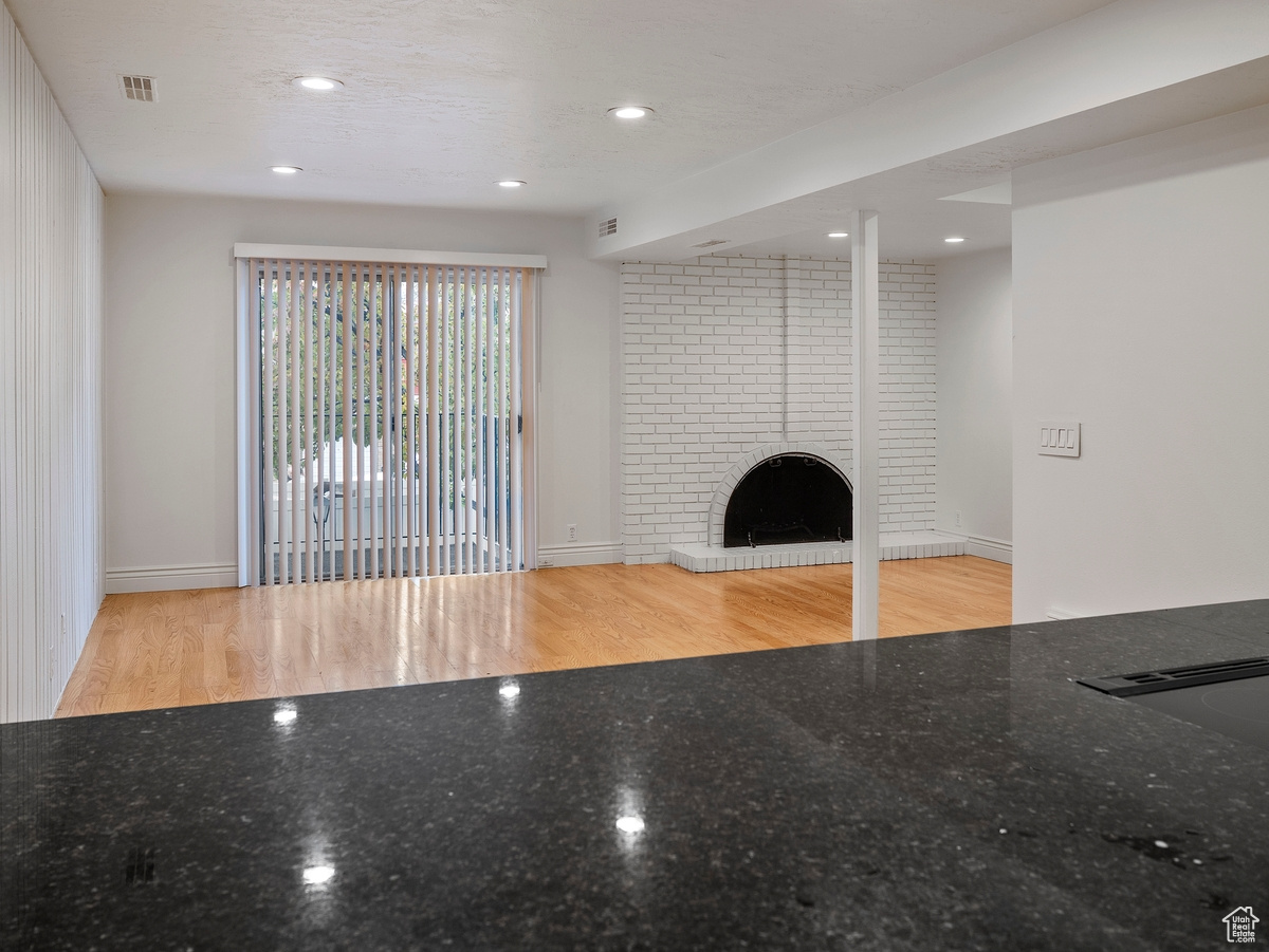 Unfurnished living room featuring a textured ceiling, light wood-type flooring, and a fireplace