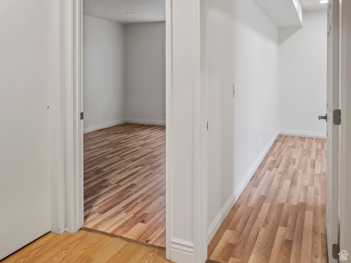 Hallway with a textured ceiling and light hardwood / wood-style floors