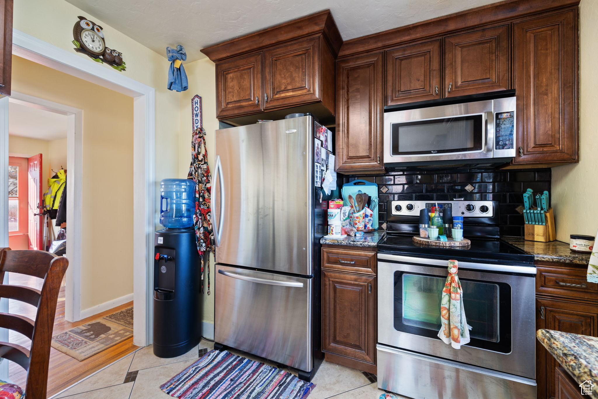 Kitchen featuring dark stone counters, backsplash, light tile patterned floors, and stainless steel appliances