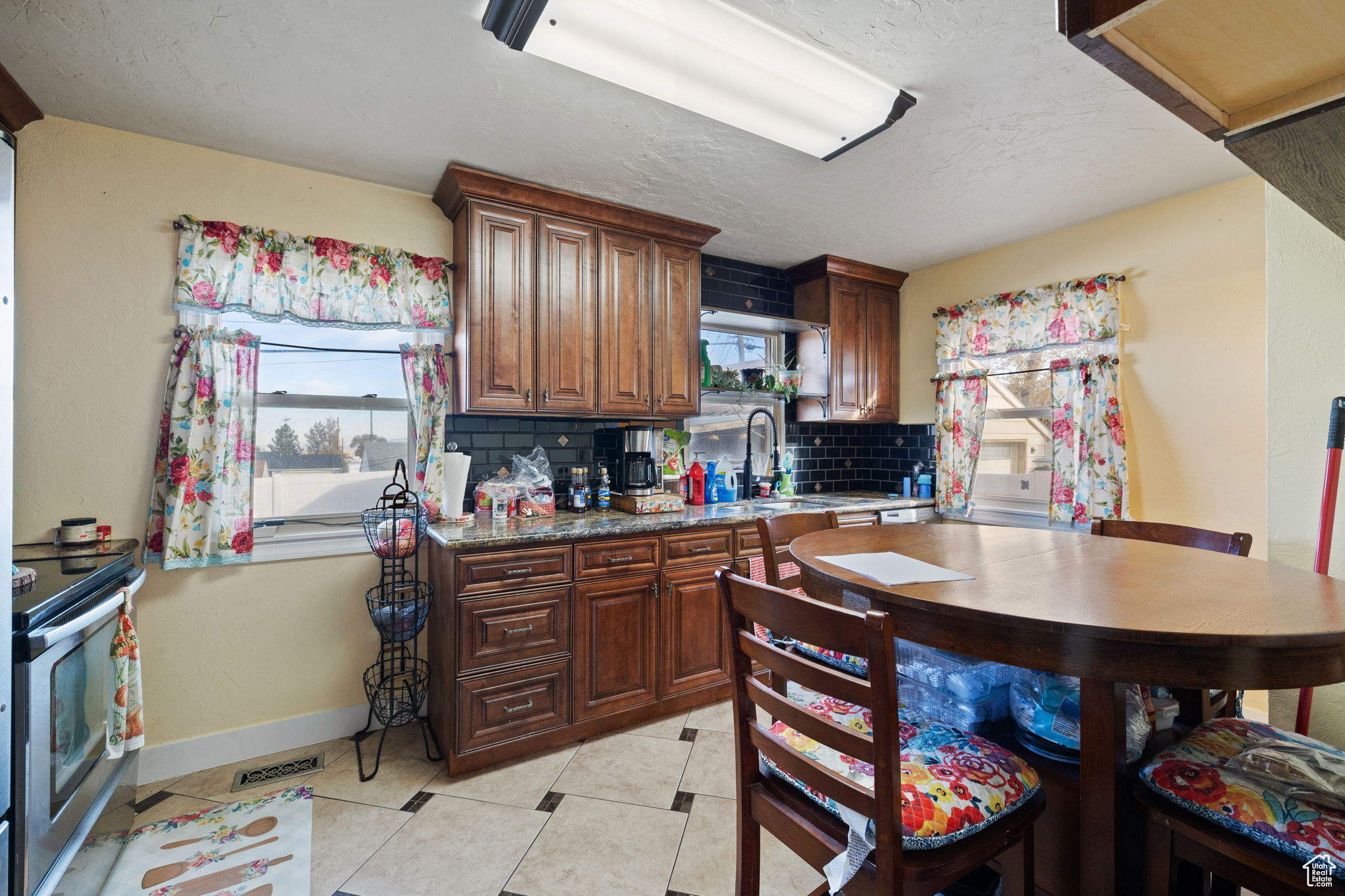 Kitchen featuring decorative backsplash, a healthy amount of sunlight, stainless steel stove, and dark stone counters