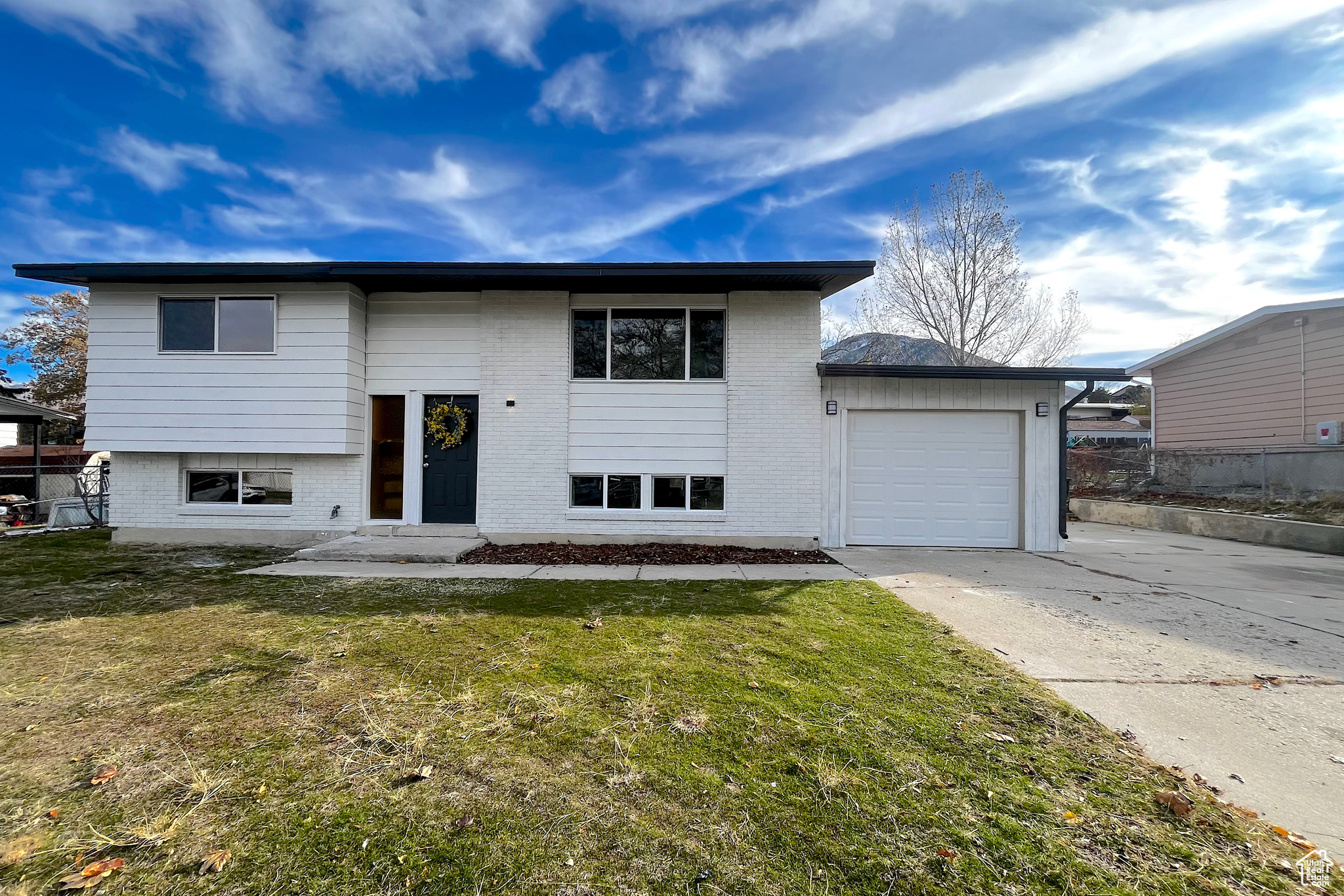 Bi-level home featuring a garage and a front yard