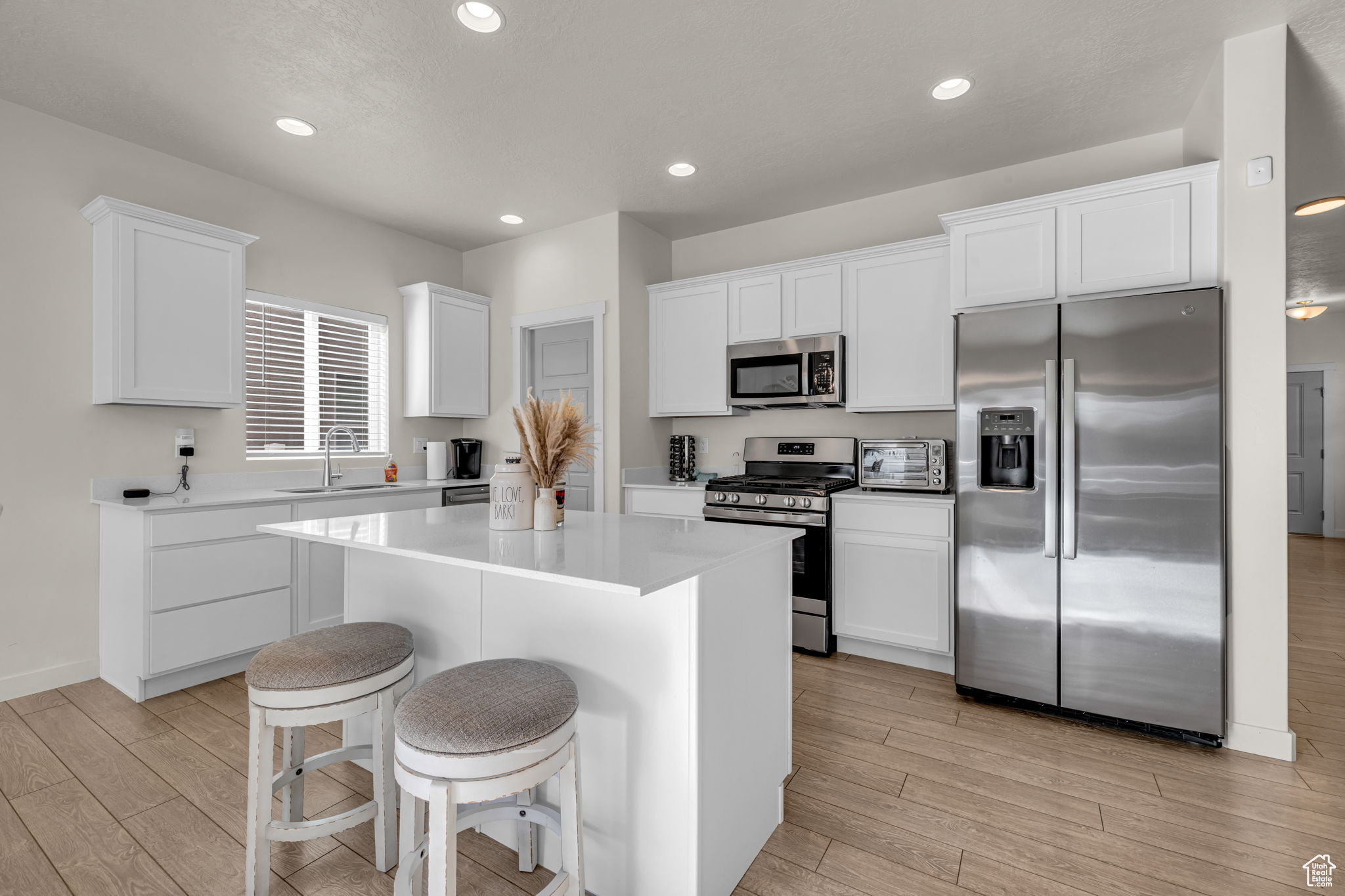 Kitchen with appliances with stainless steel finishes, sink, a center island, white cabinetry, and a breakfast bar area