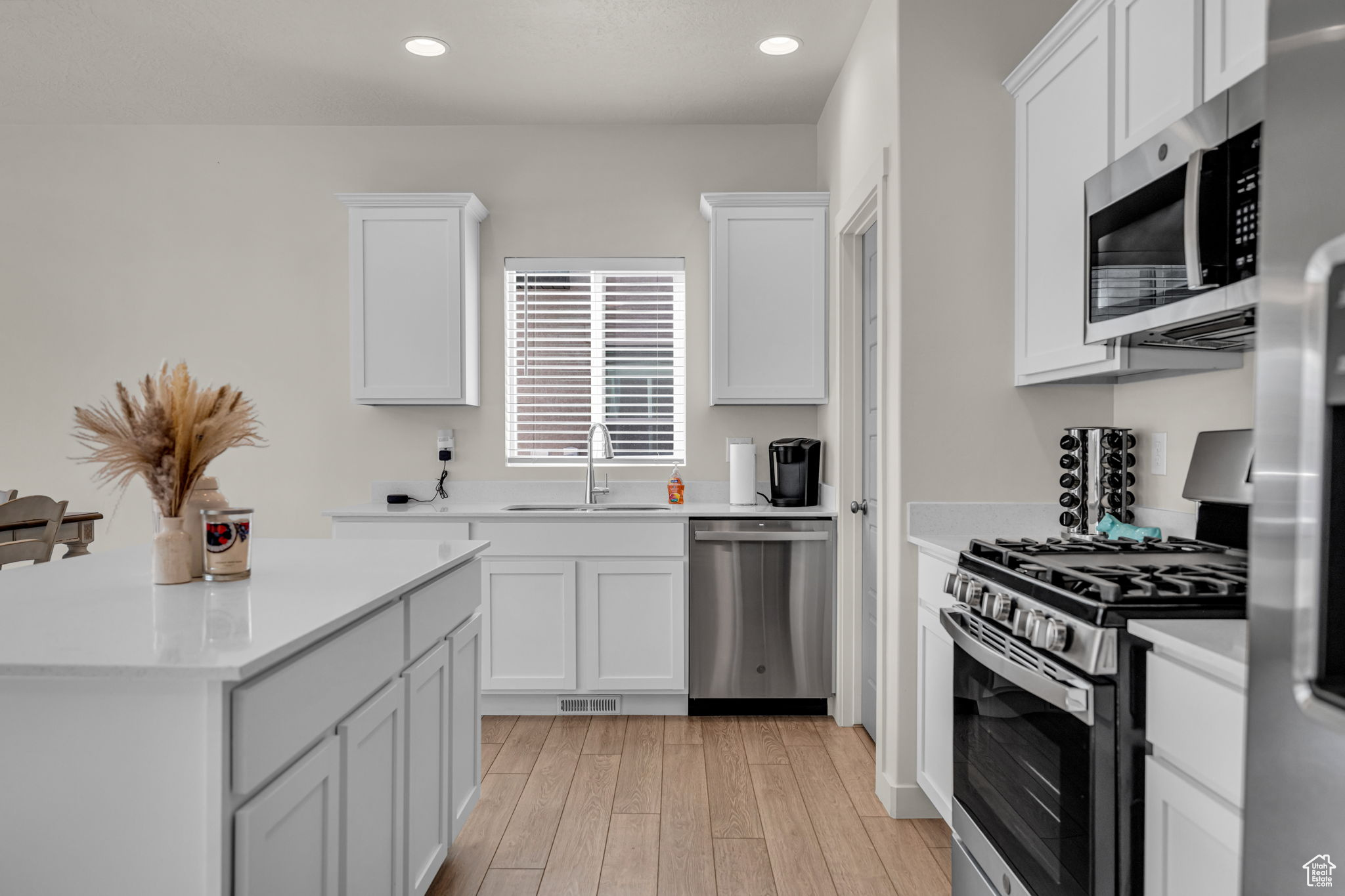 Kitchen with white cabinetry, sink, and appliances with stainless steel finishes