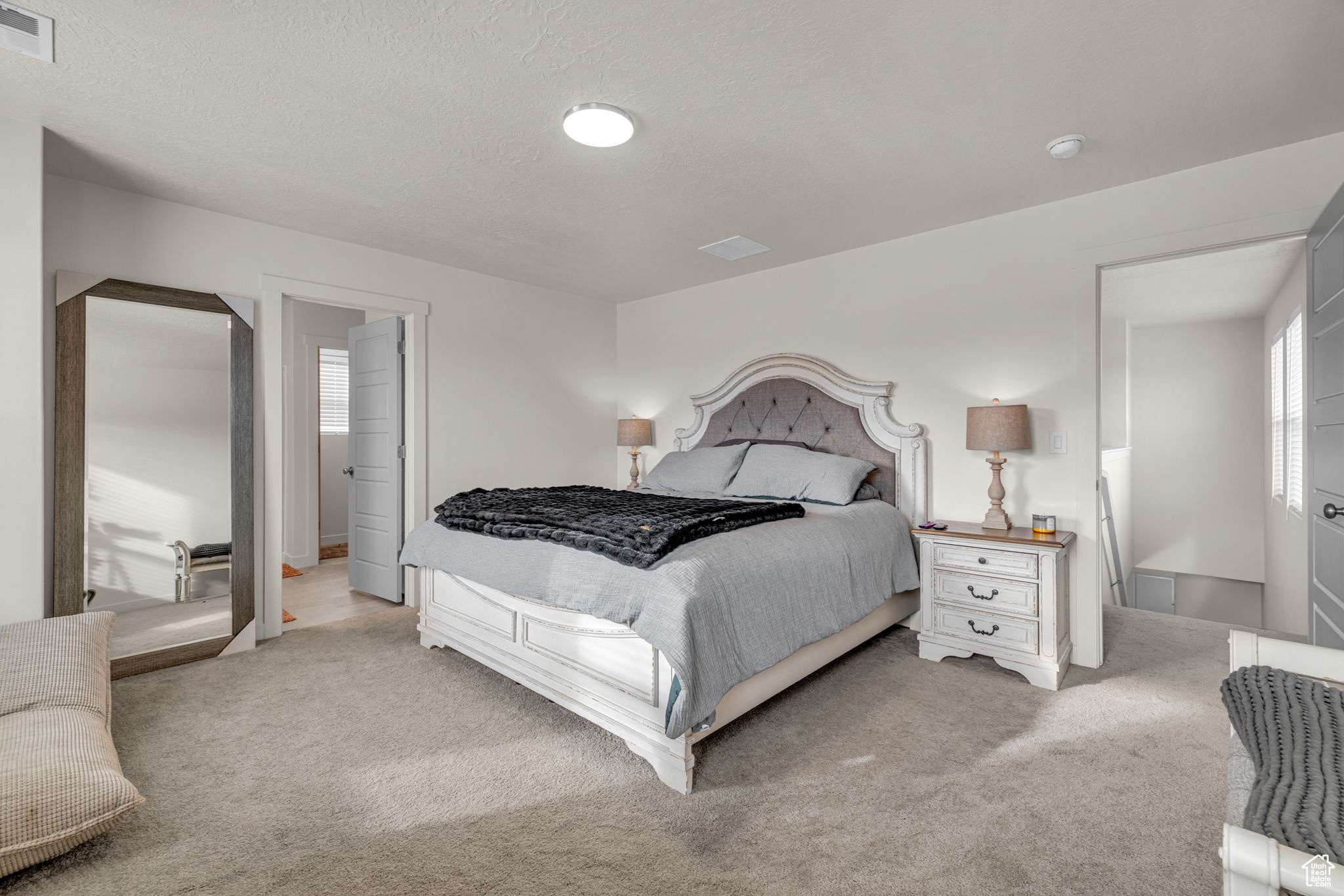 Bedroom with a textured ceiling and light carpet