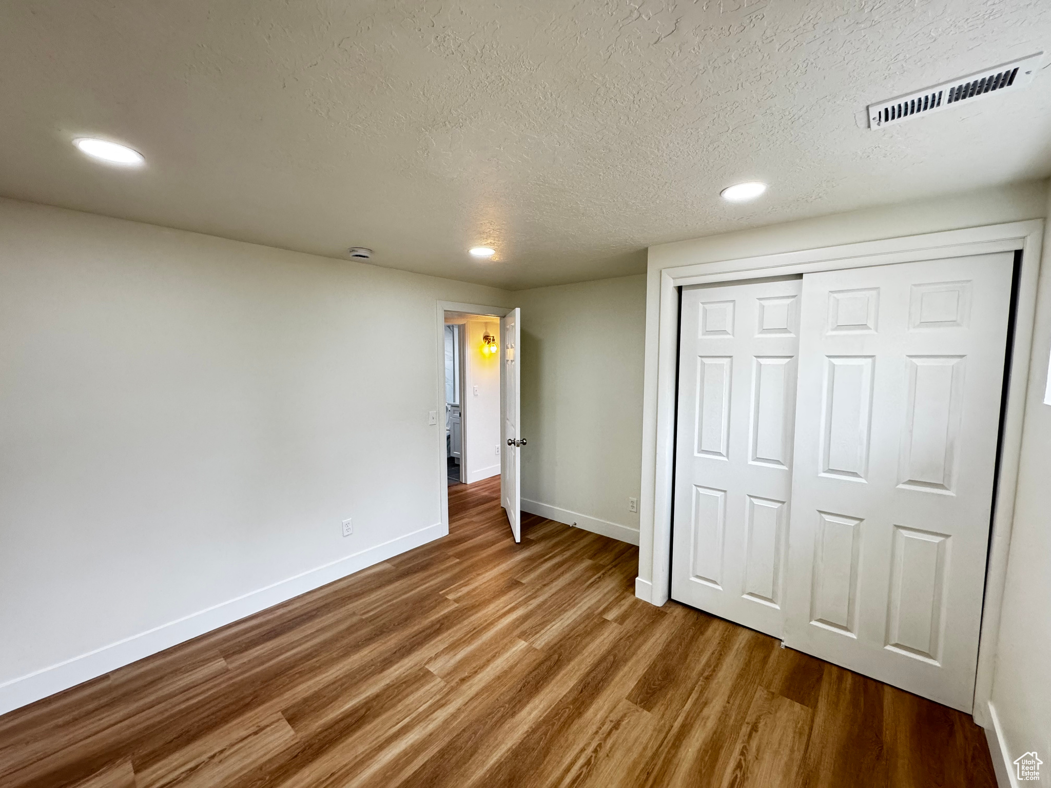 Unfurnished bedroom with a closet, wood-type flooring, and a textured ceiling