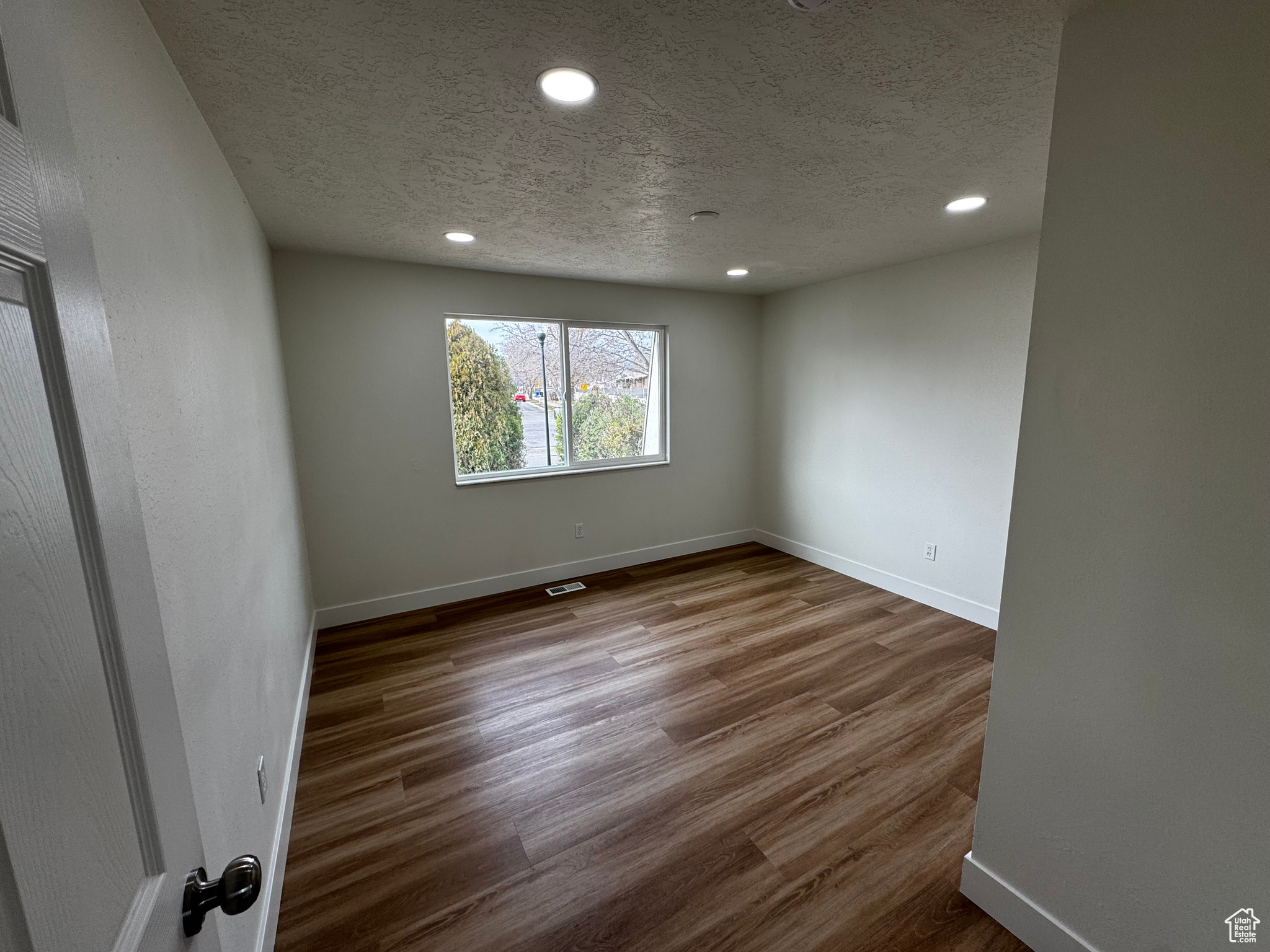 Empty room featuring a textured ceiling and hardwood / wood-style flooring