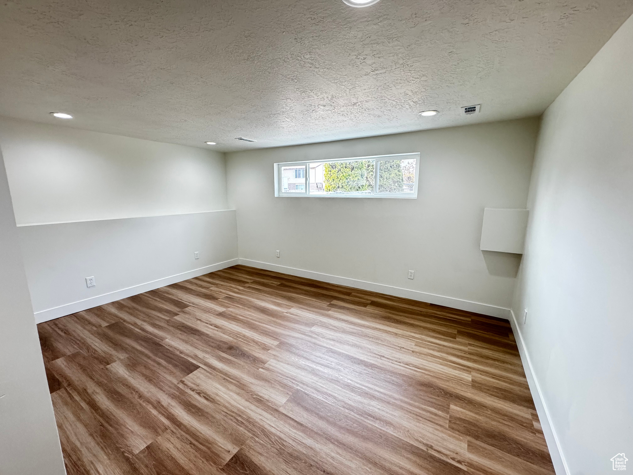 Empty room featuring light hardwood / wood-style flooring and a textured ceiling