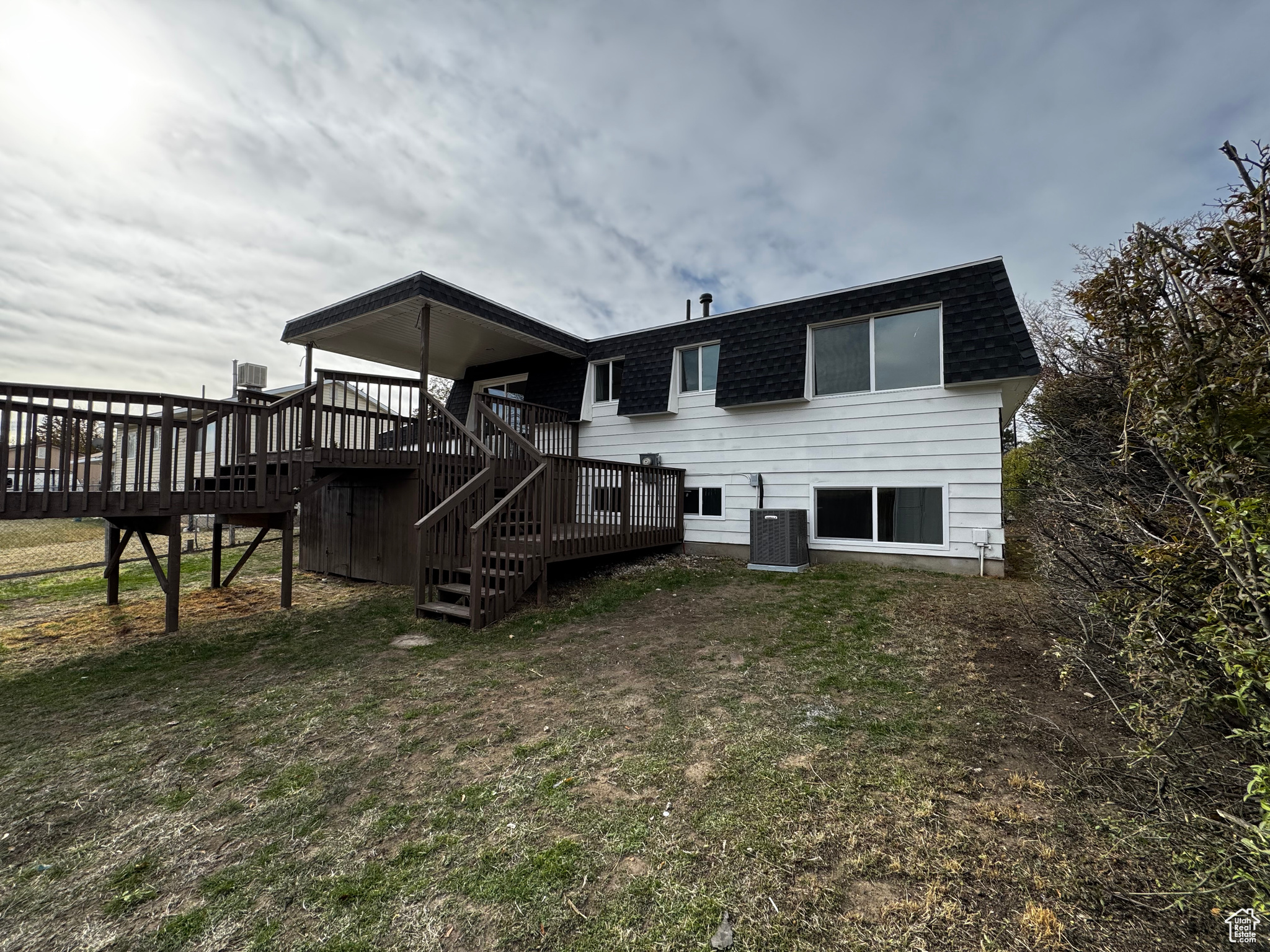 Rear view of property featuring central AC unit, a deck, and a yard