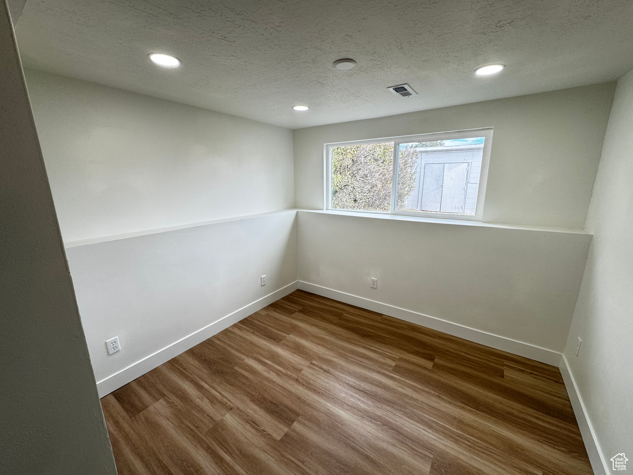 Unfurnished room featuring hardwood / wood-style floors and a textured ceiling