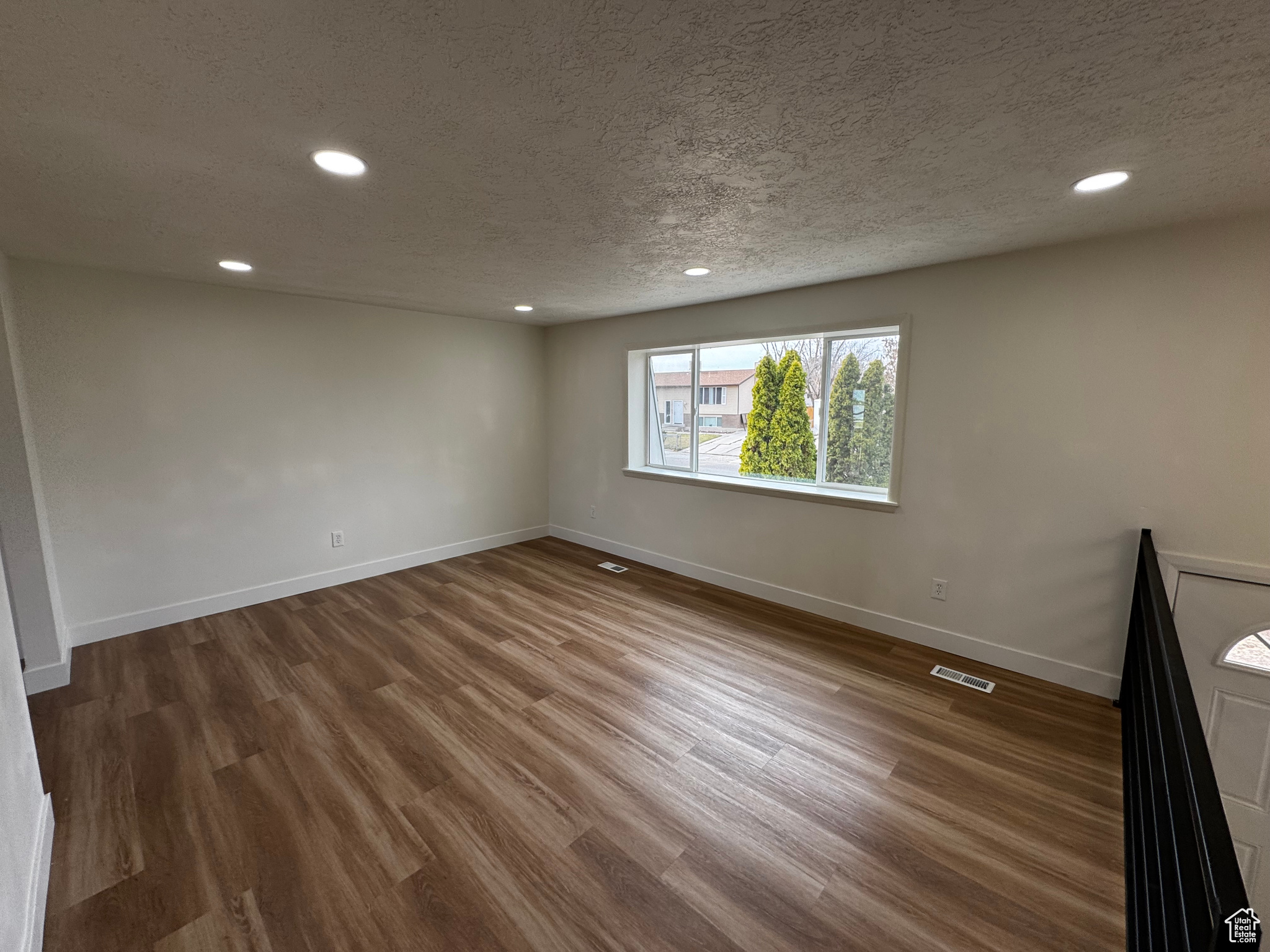 Unfurnished room with dark hardwood / wood-style floors and a textured ceiling