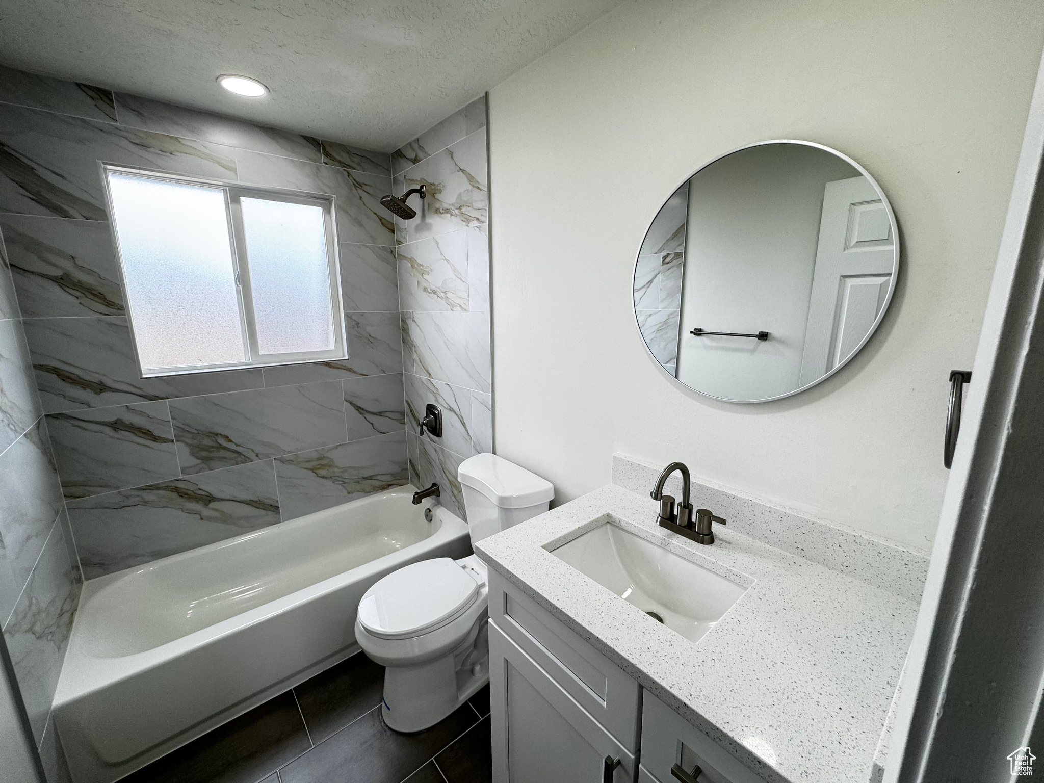 Full bathroom featuring vanity, tiled shower / bath combo, tile patterned floors, and toilet