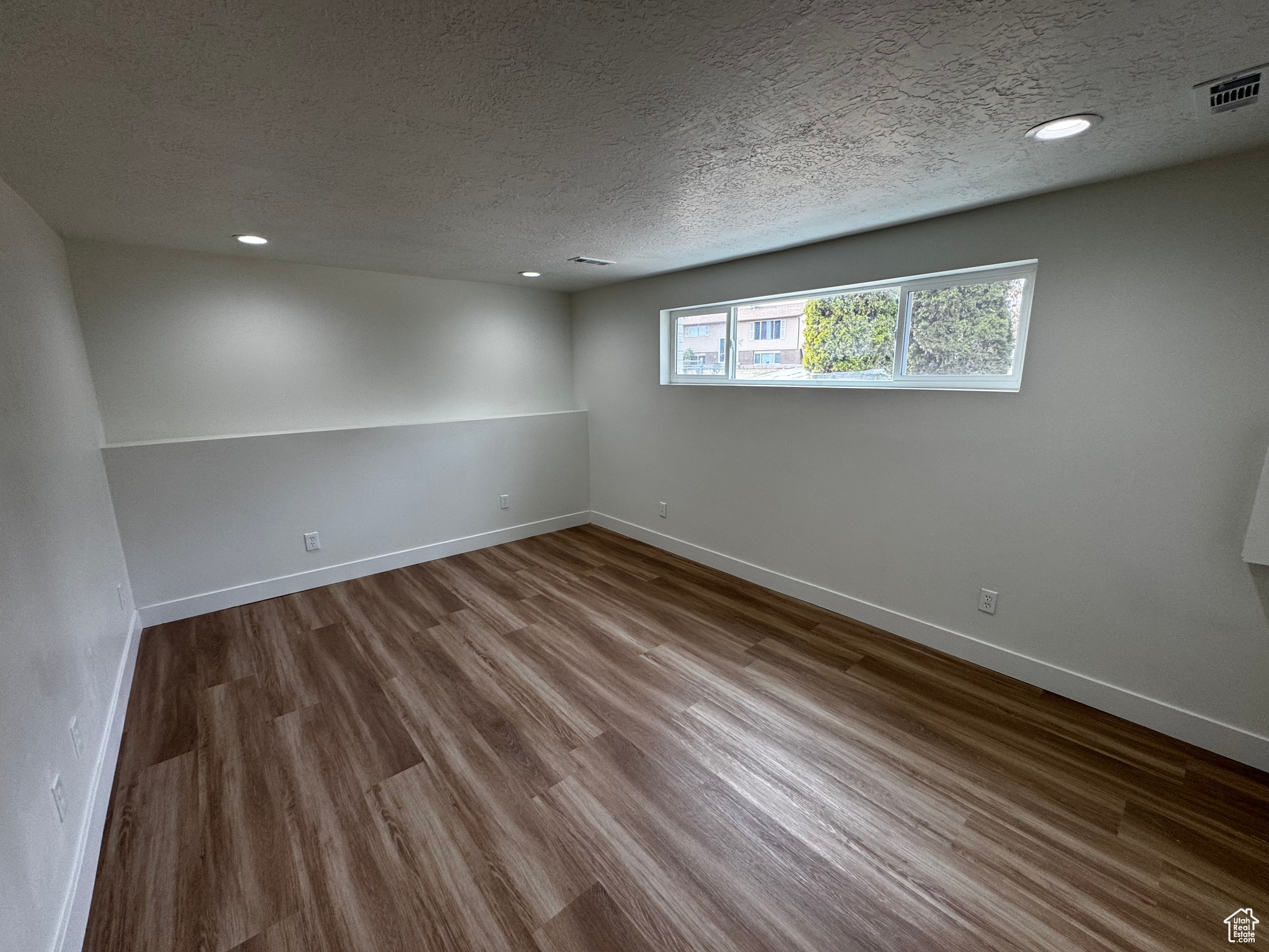 Unfurnished room featuring hardwood / wood-style floors and a textured ceiling