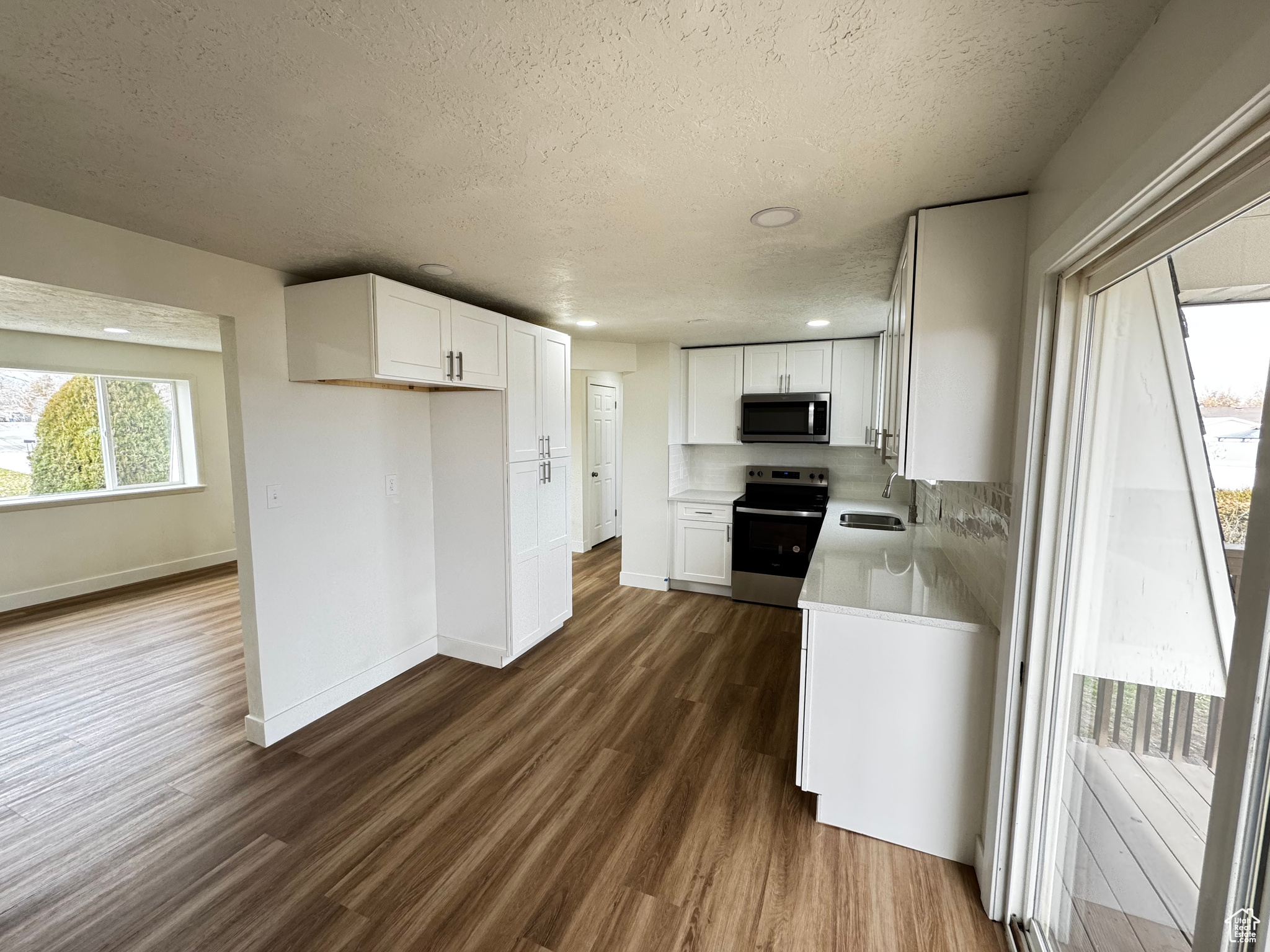 Kitchen with dark hardwood / wood-style floors, white cabinetry, and appliances with stainless steel finishes