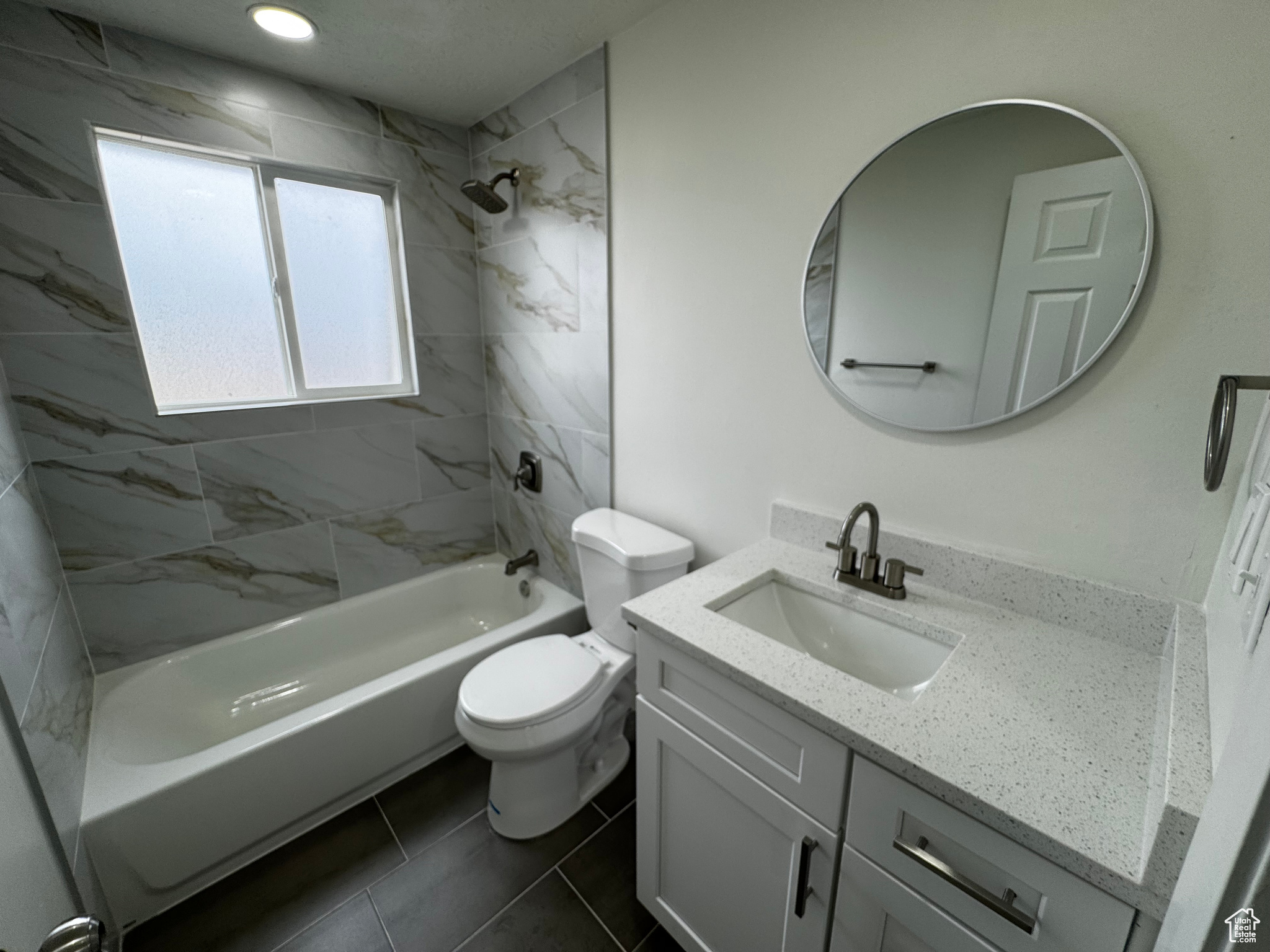 Full bathroom with toilet, tile patterned flooring, vanity, and tiled shower / bath