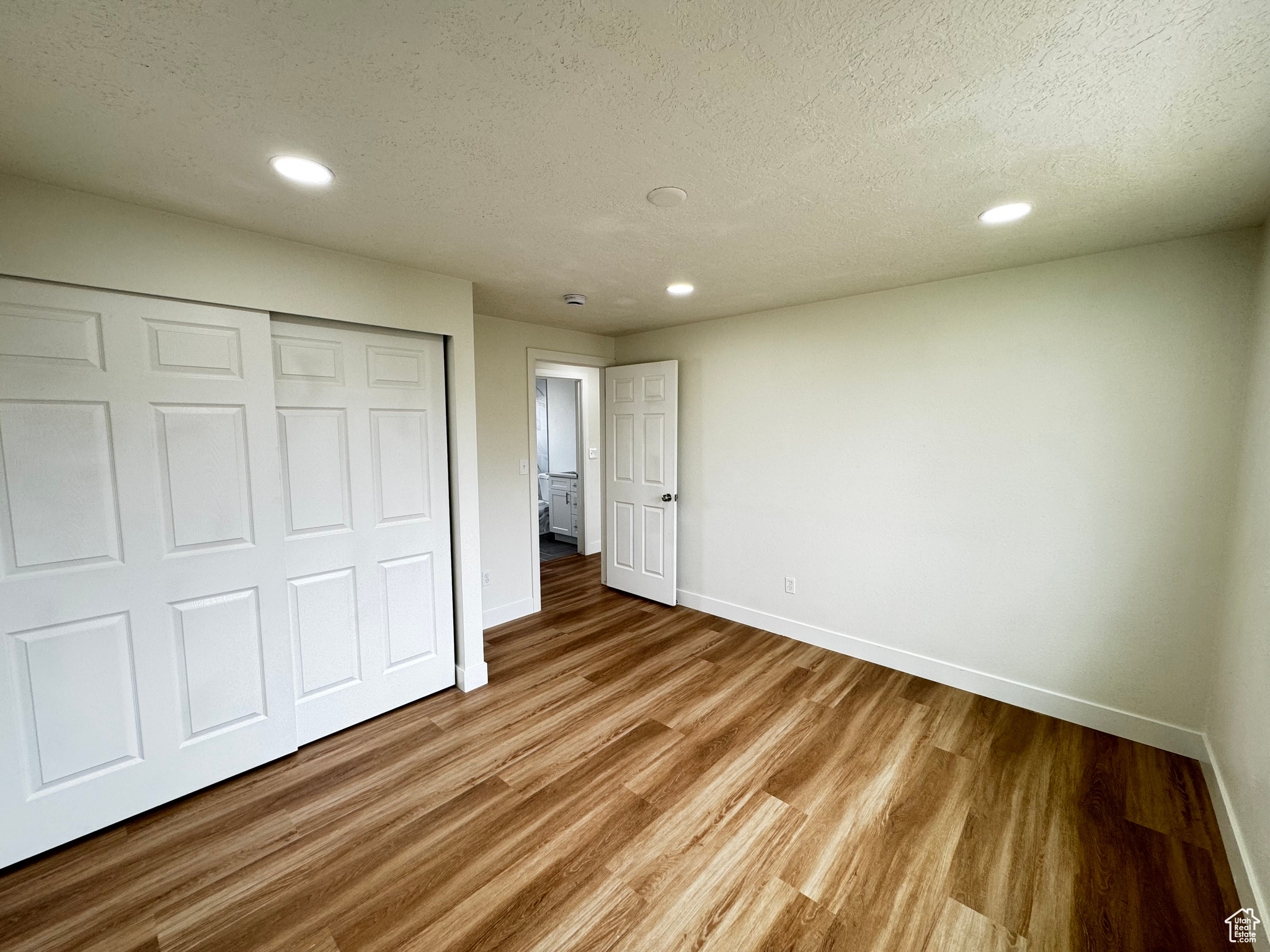 Unfurnished bedroom featuring a closet, a textured ceiling, and hardwood / wood-style flooring