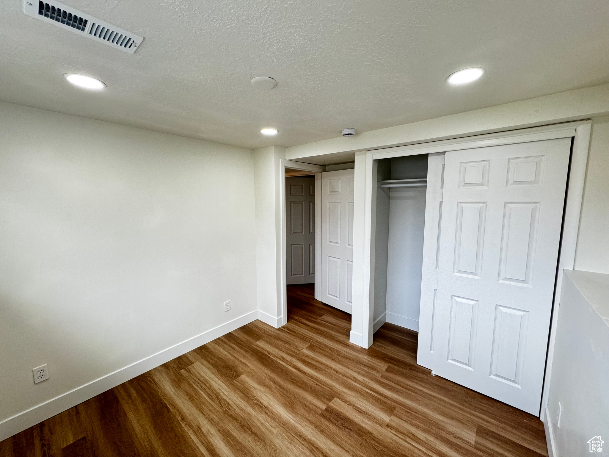 Unfurnished bedroom with wood-type flooring, a textured ceiling, and a closet