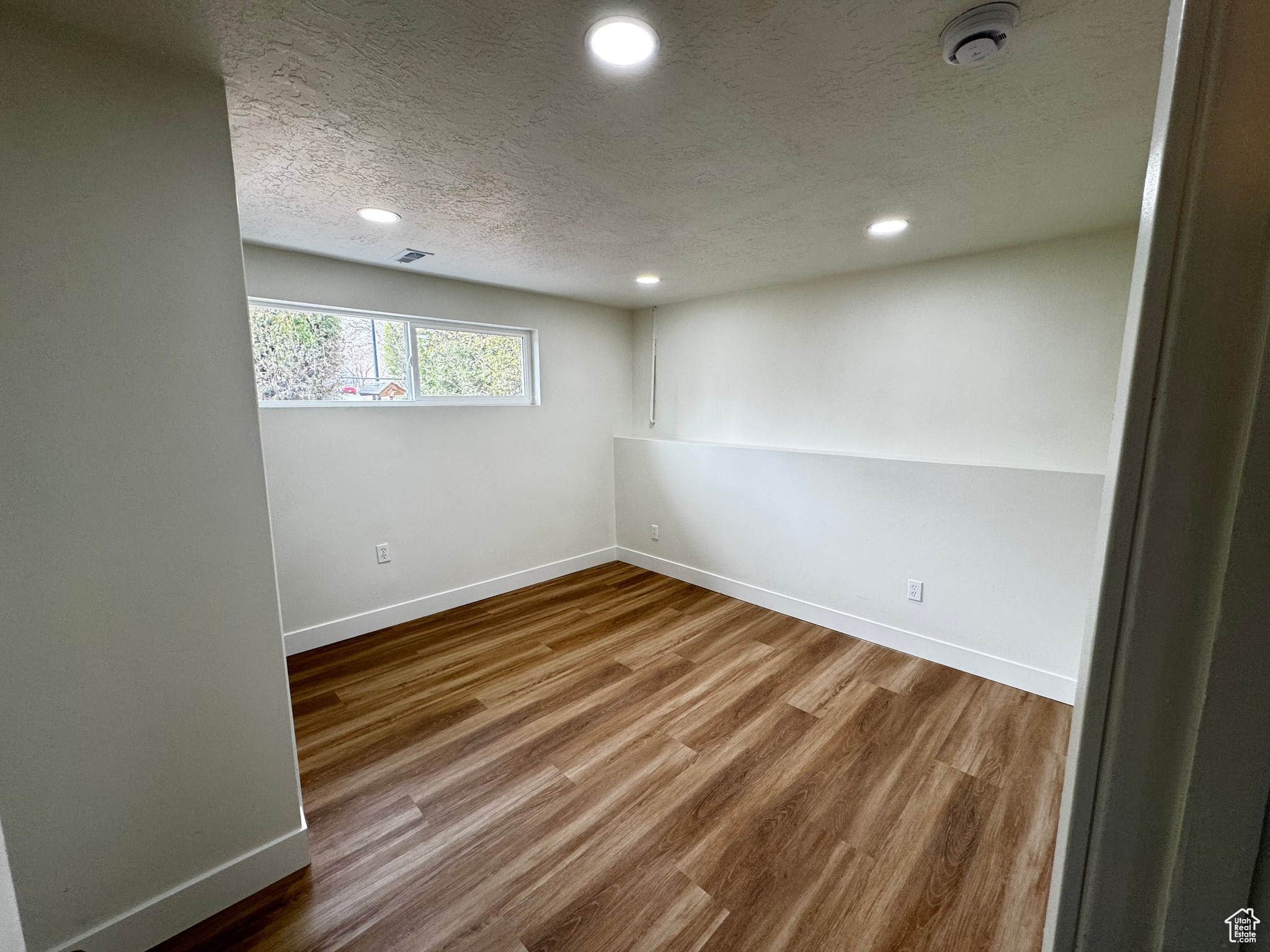 Spare room with a textured ceiling and hardwood / wood-style flooring