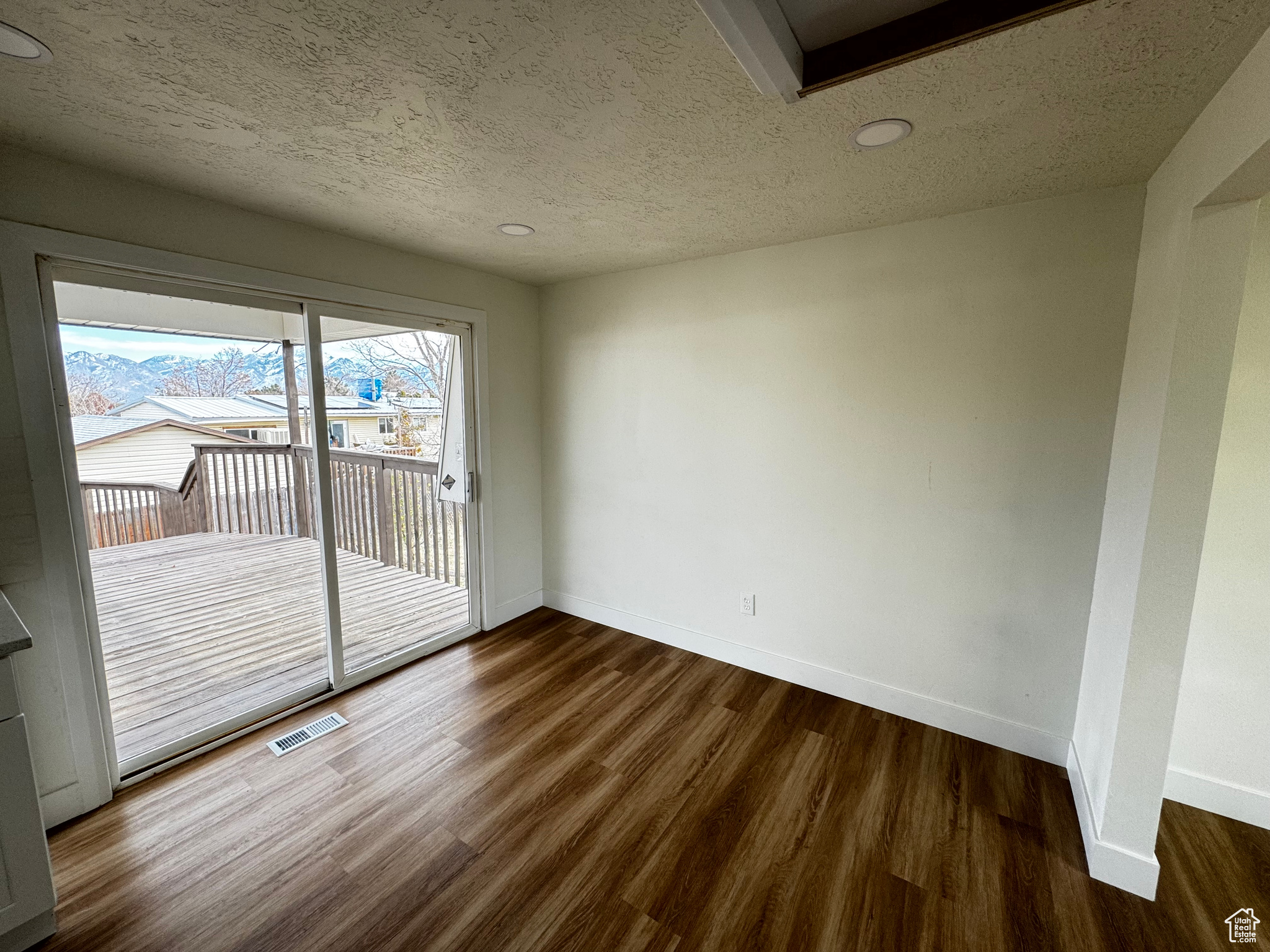 Empty room with dark hardwood / wood-style flooring and a textured ceiling