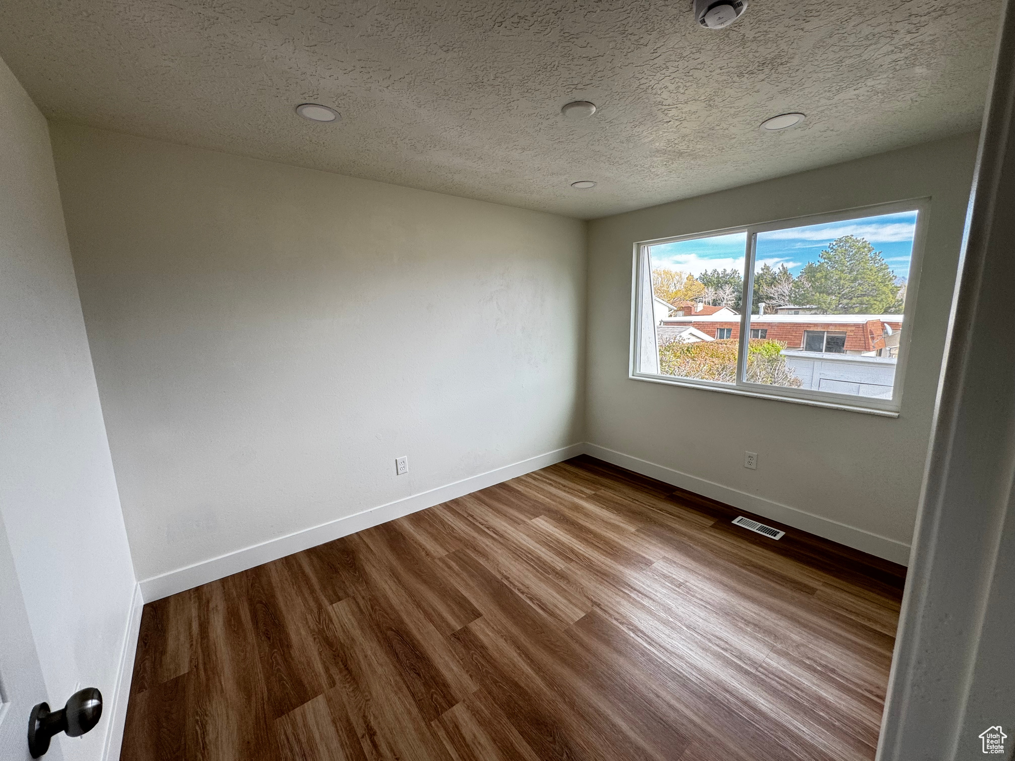 Empty room with wood-type flooring and a textured ceiling