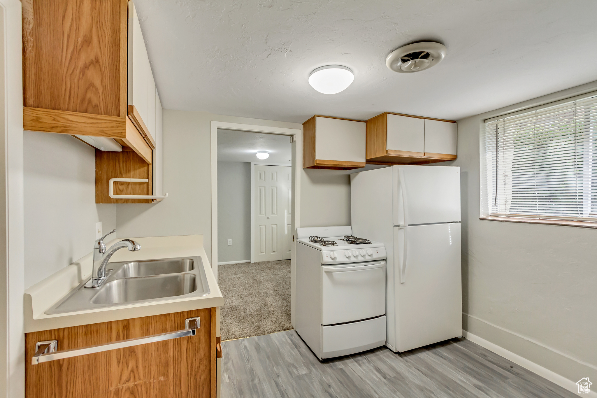 Kitchen featuring light hardwood / wood-style flooring, white cabinets, white appliances, and sink