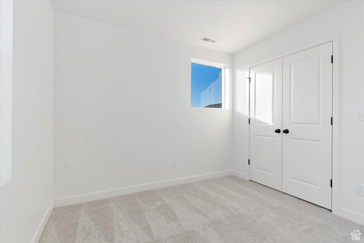 Unfurnished bedroom featuring a closet and light colored carpet