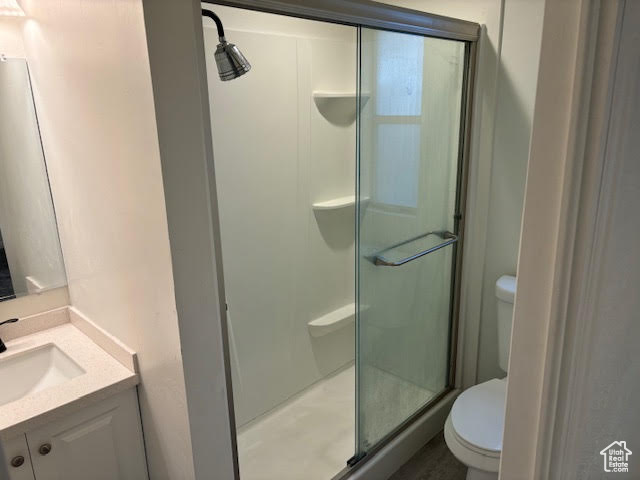 Bathroom with an enclosed shower, vanity, and toilet