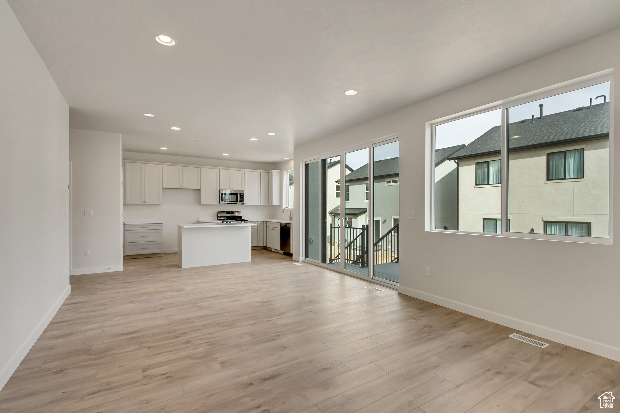 Kitchen with sink, a kitchen island, light hardwood / wood-style flooring, white cabinets, and appliances with stainless steel finishes