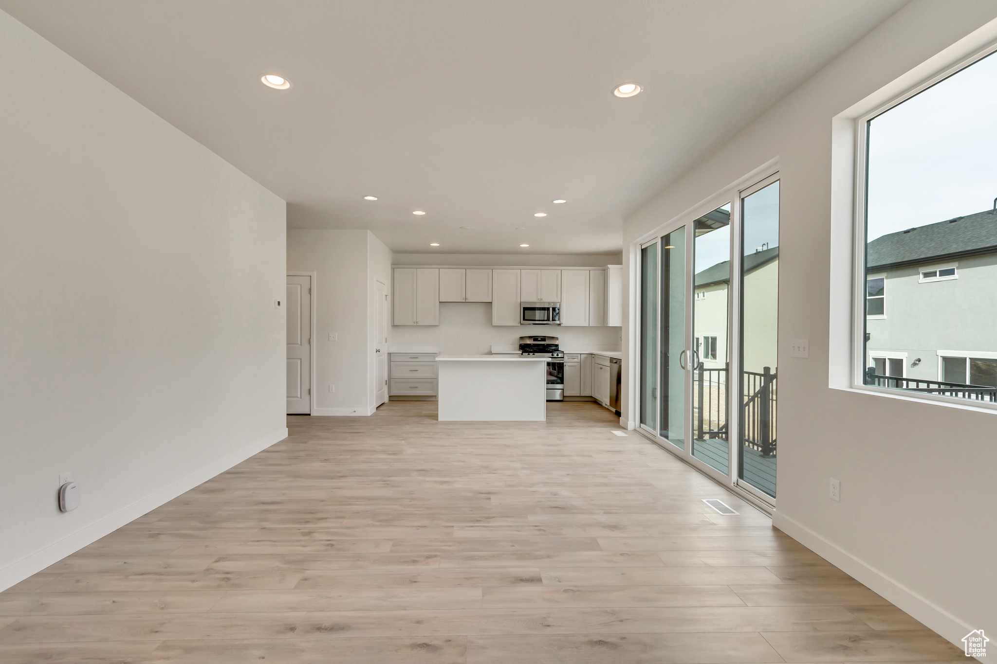 Kitchen with light hardwood / wood-style floors, a kitchen island, white cabinetry, and appliances with stainless steel finishes