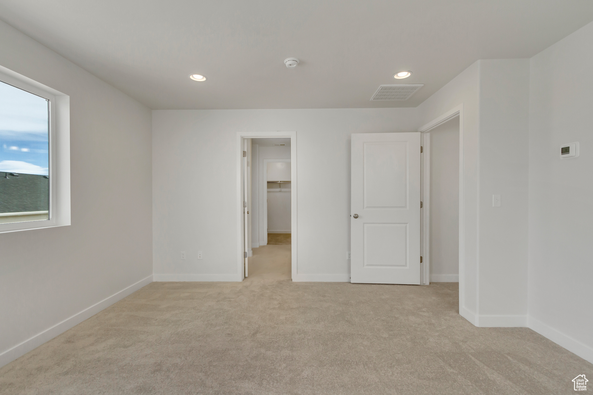 Unfurnished bedroom with a spacious closet, a closet, and light carpet