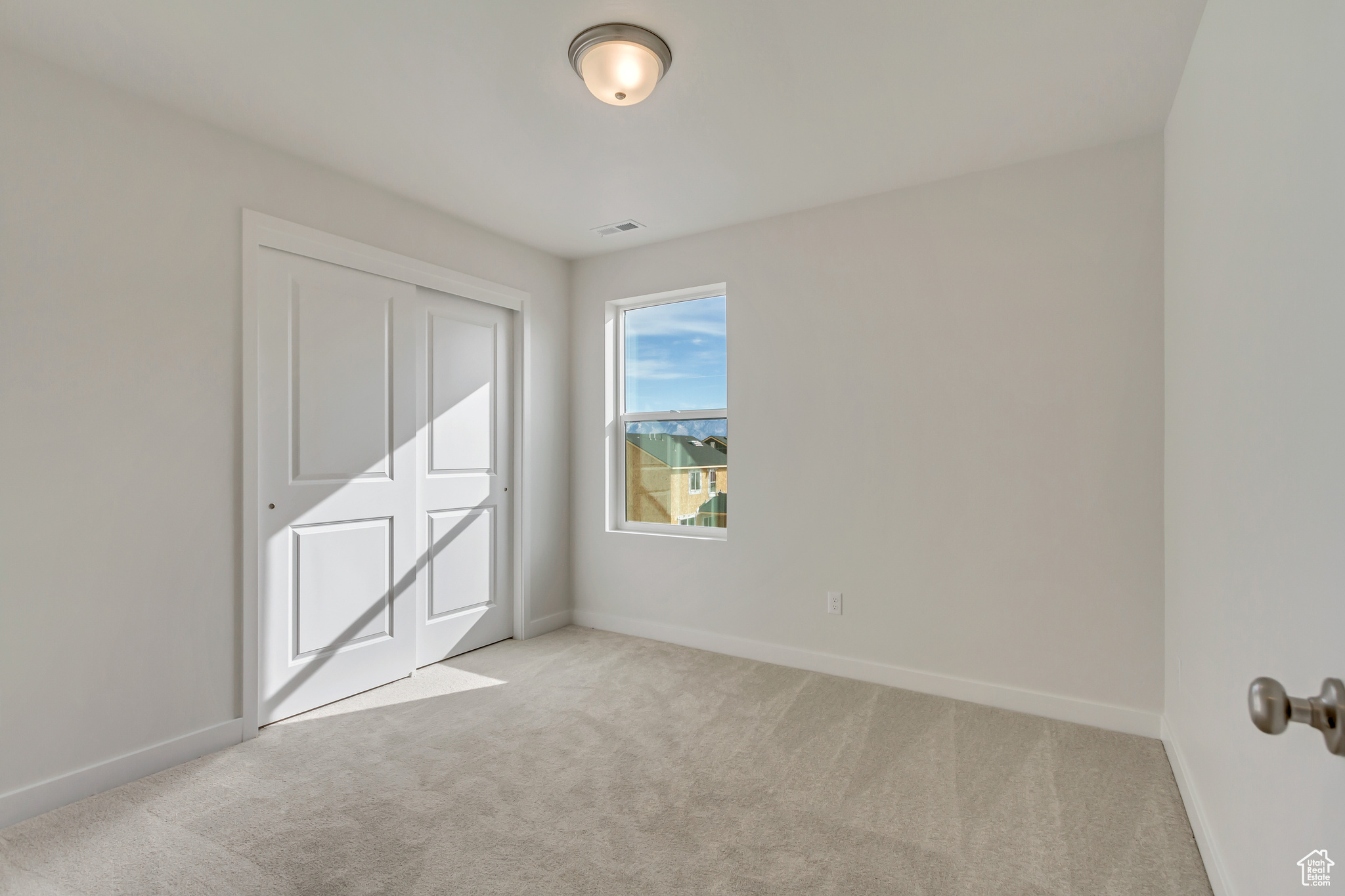 Unfurnished bedroom featuring light colored carpet and a closet