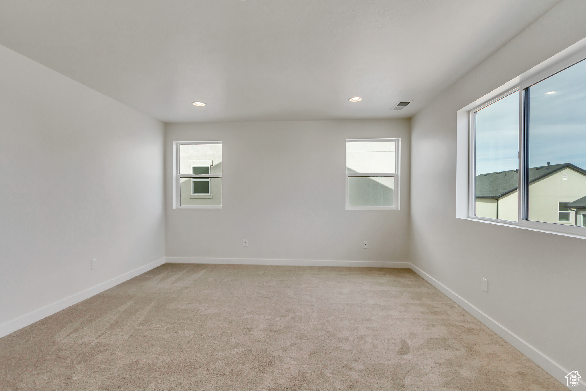 Spare room featuring light colored carpet and a wealth of natural light