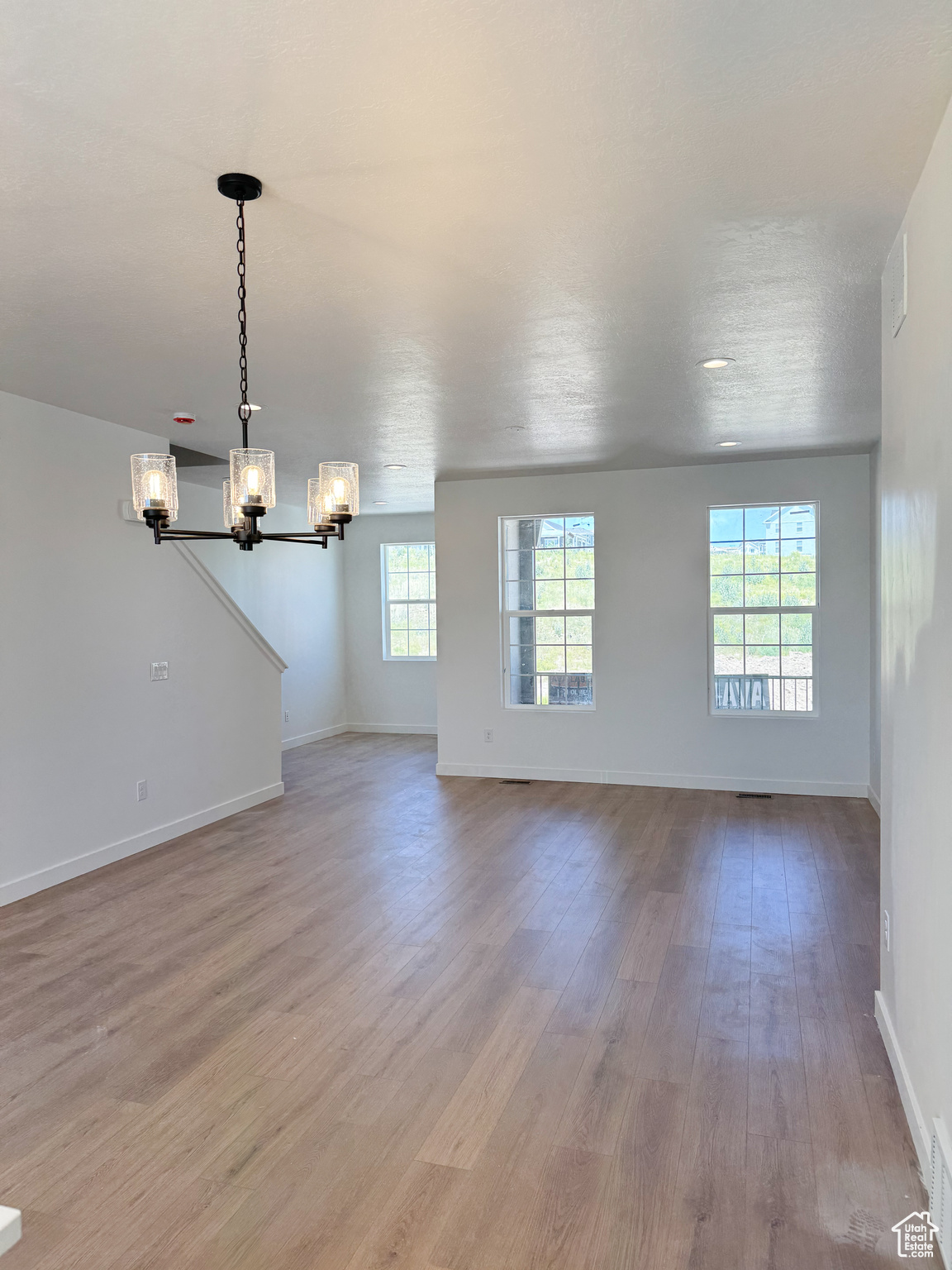 Unfurnished living room featuring a chandelier and light hardwood / wood-style flooring