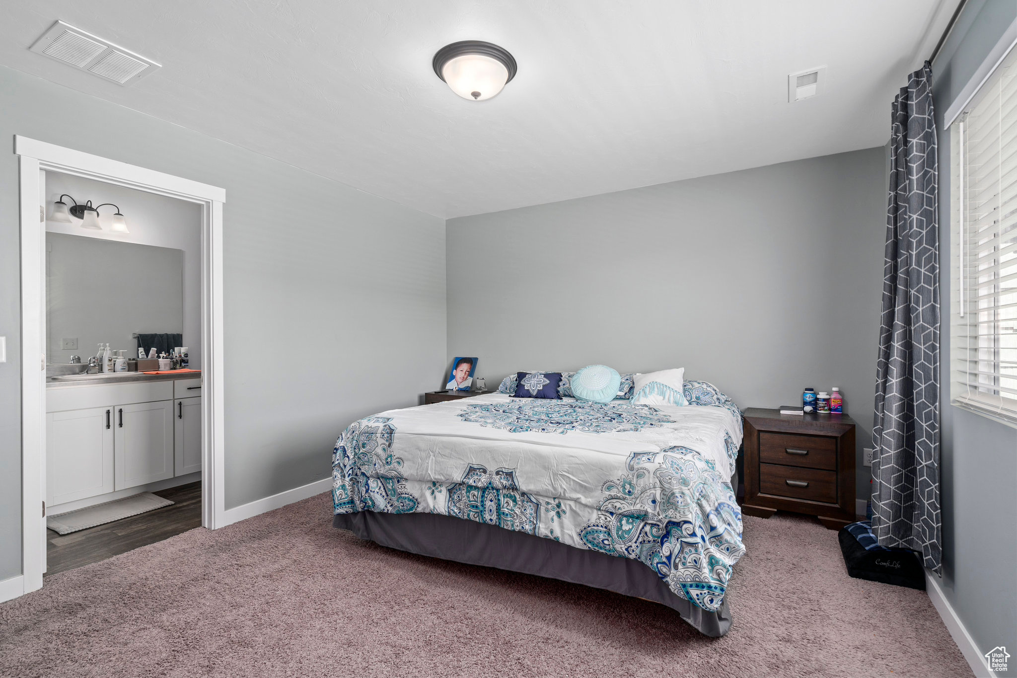 Carpeted bedroom featuring ensuite bath and sink